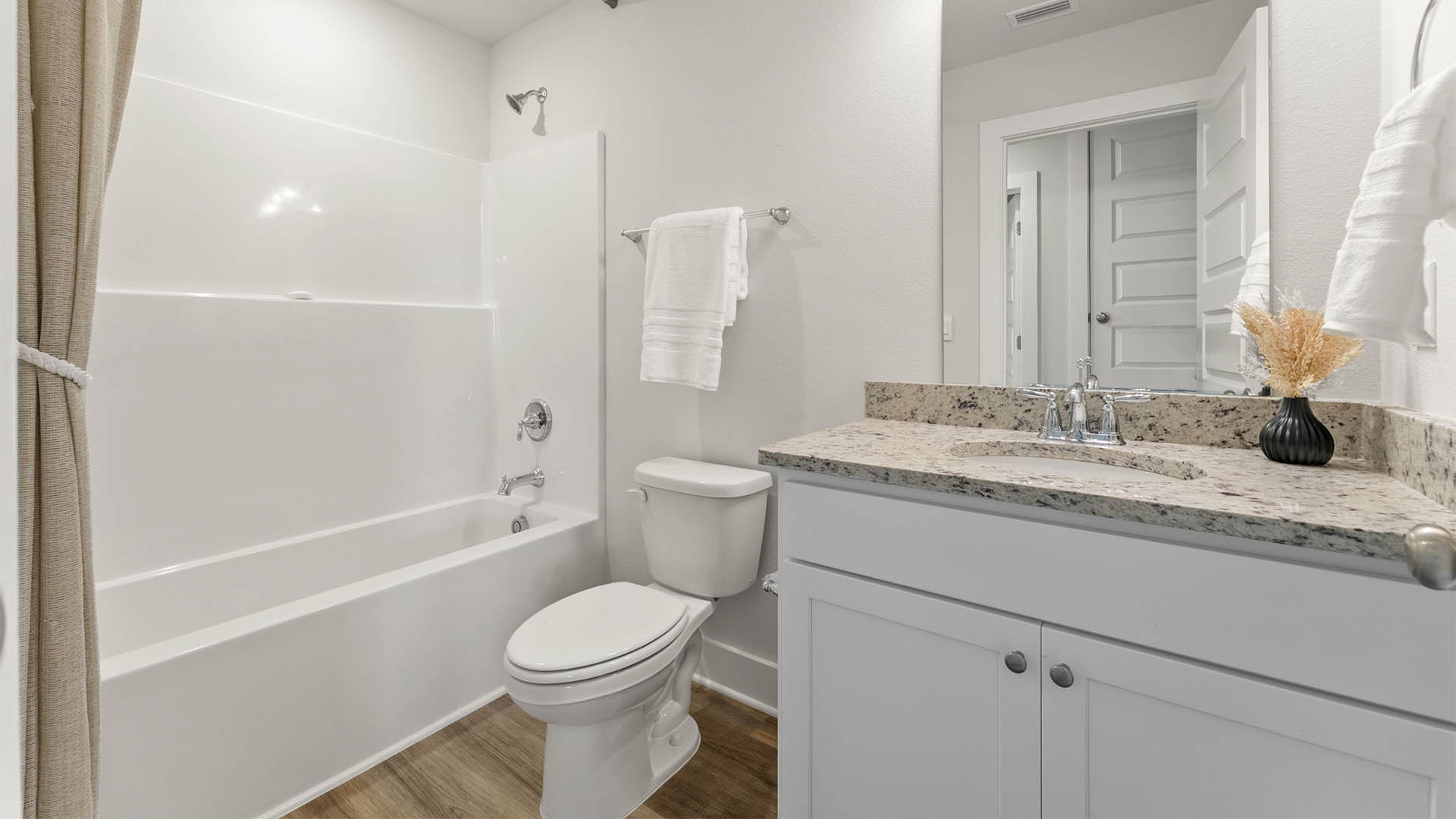 Bathroom with single vanity granite countertops and white cabinets and toilet and shower.