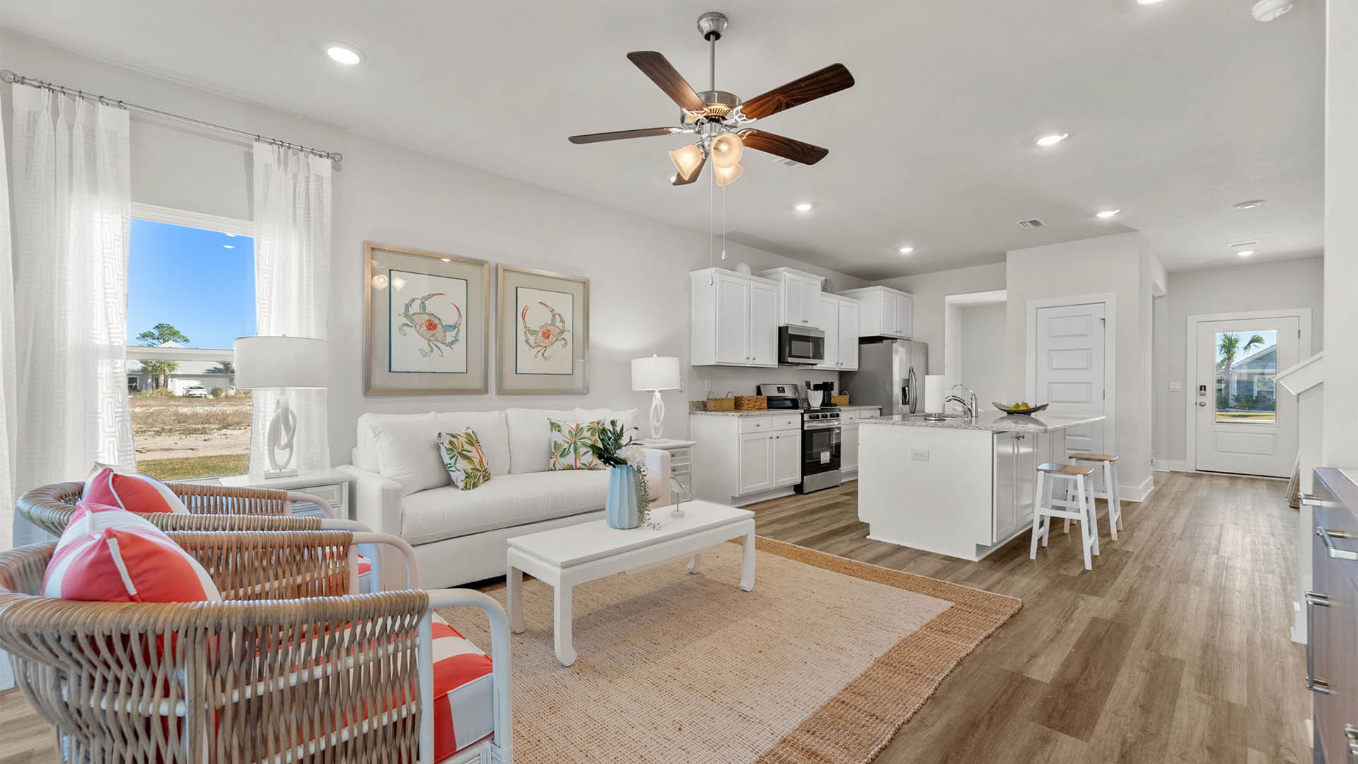 Living room with ceiling fan and EVP flooring and kitchen.
