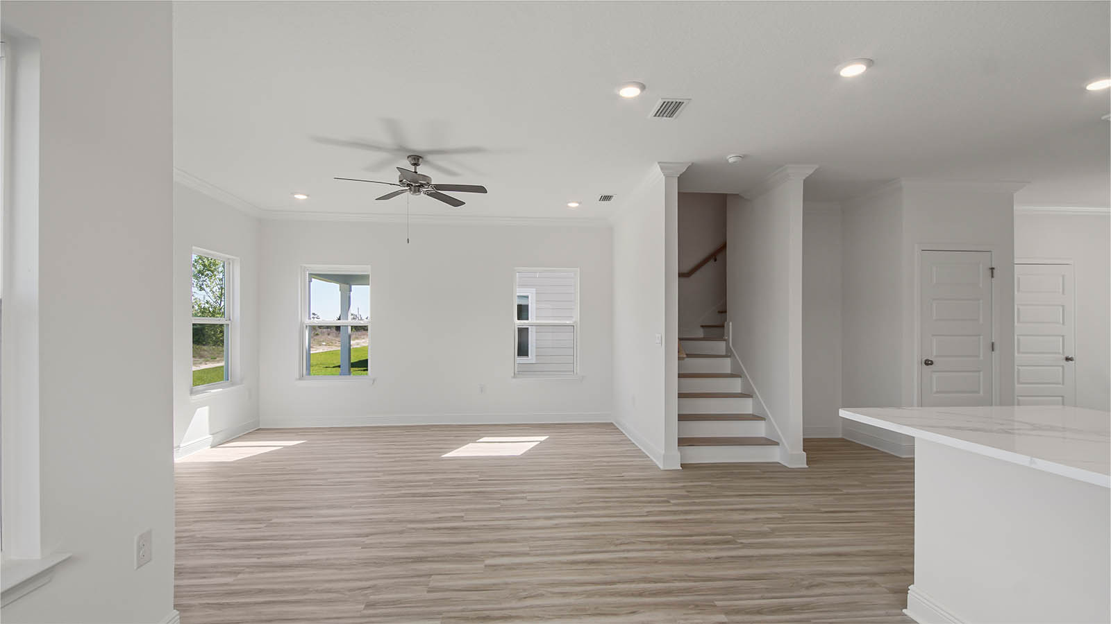 Living room with EVP flooring and ceiling fan and stairs.