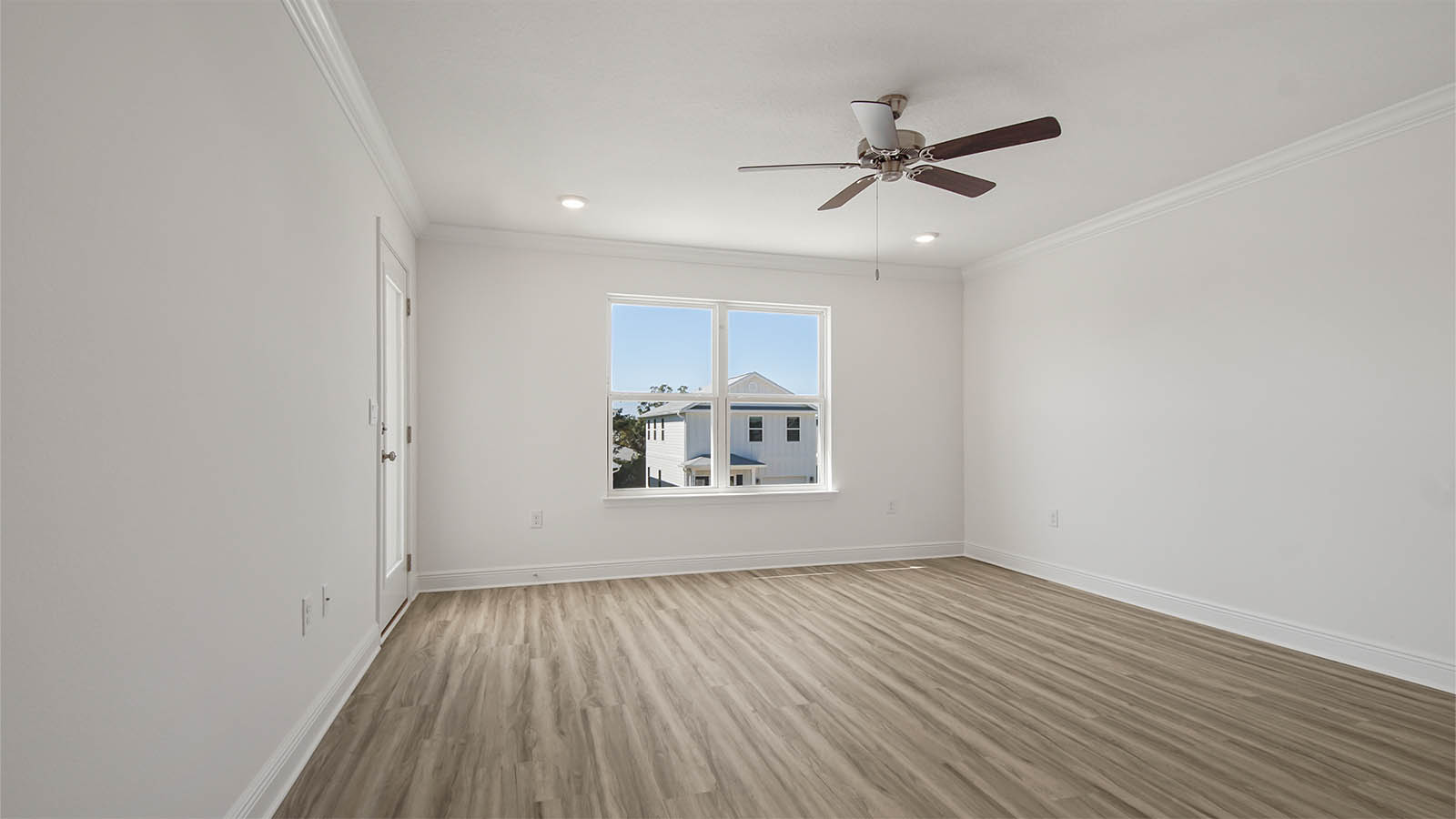 Primary bedroom with EVP flooring and balcony door and ceiling fan.