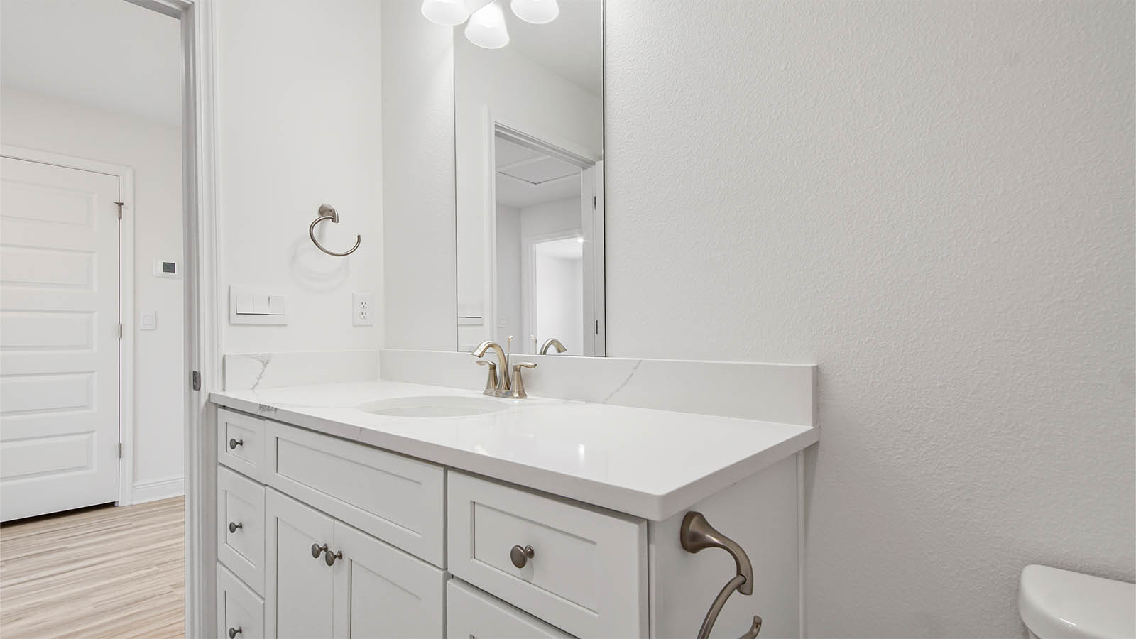 Bathroom with EVP flooring and single vanity quartz countertops and white cabinets.