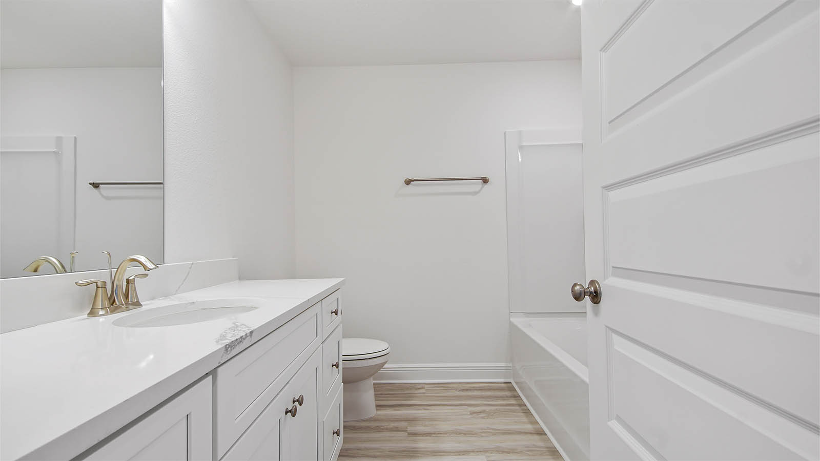 Bathroom with EVP flooring and single vanity quartz countertops and white cabinets.