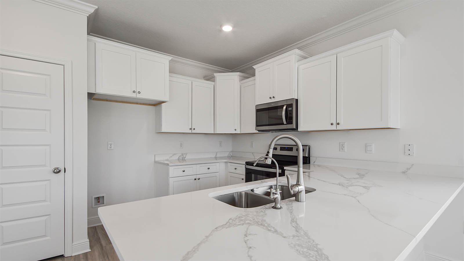 Kitchen with quartz countertops and white cabinets and stainless steel appliances.