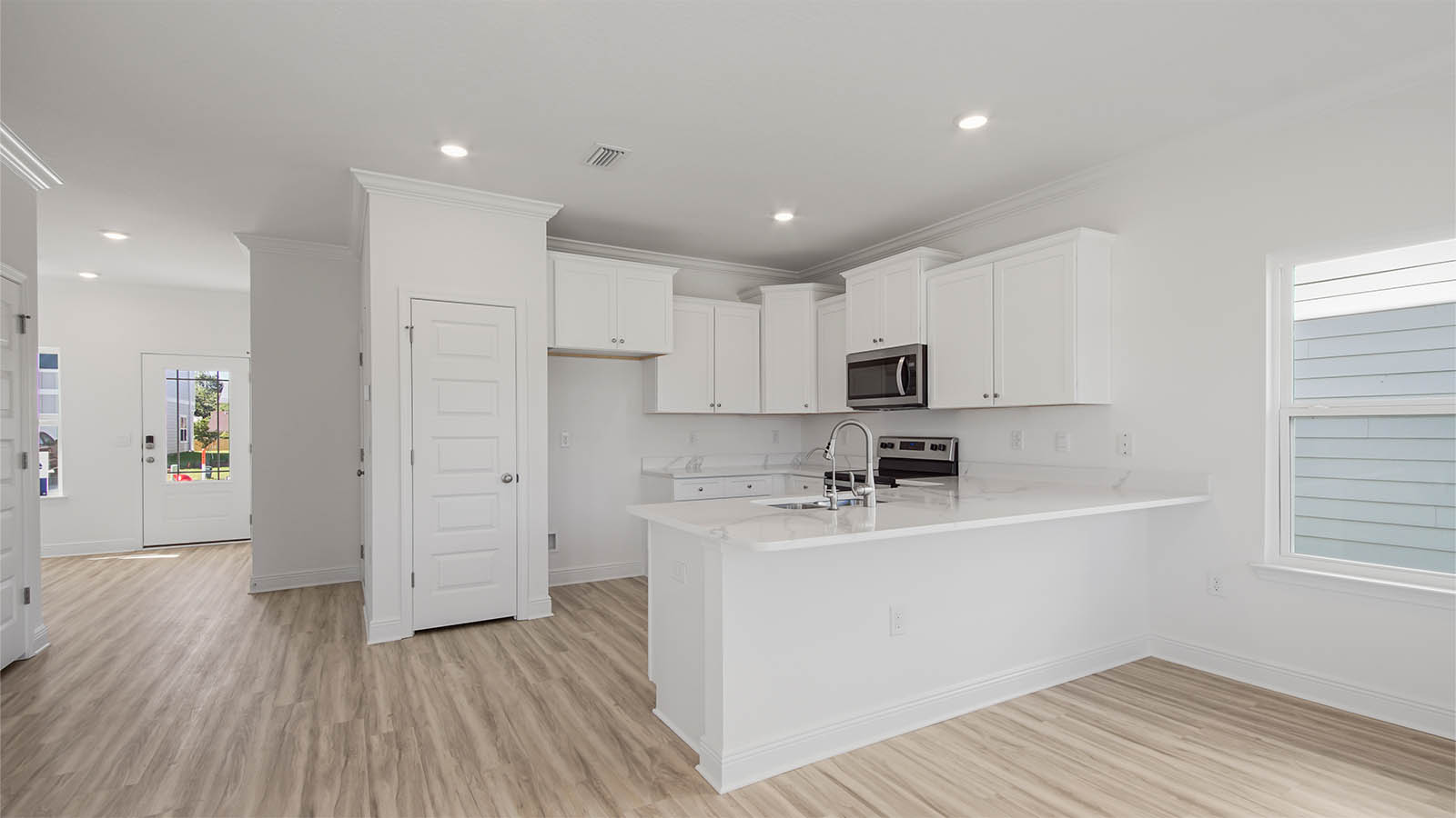 Kitchen with quartz countertops and white cabinets and stainless steel appliances.