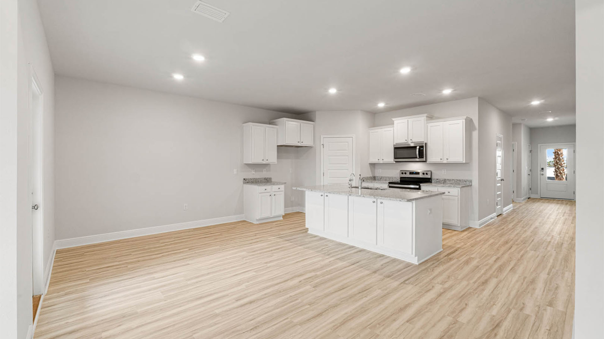 Kitchen with island and granite countertops and white cabinets and stainless-steel appliances and dining area.