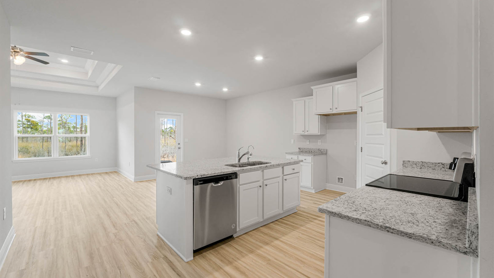 Kitchen with island and granite countertops and white cabinets and stainless-steel appliances.