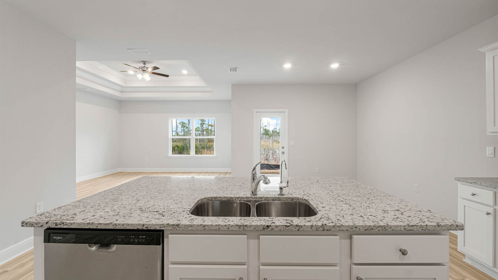Kitchen with island and granite countertops and white cabinets and stainless-steel appliances.