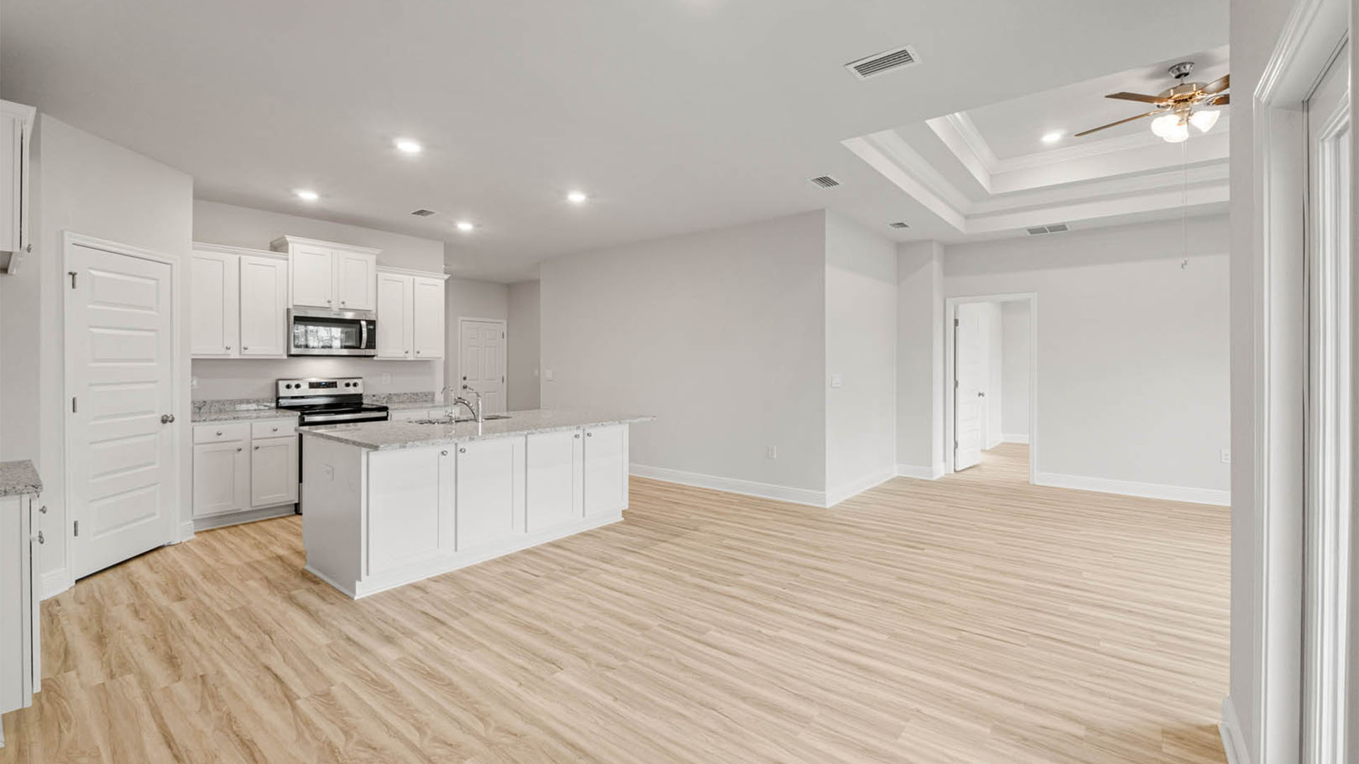 Kitchen with island and granite countertops and white cabinets and stainless-steel appliances and dining area with open living room.