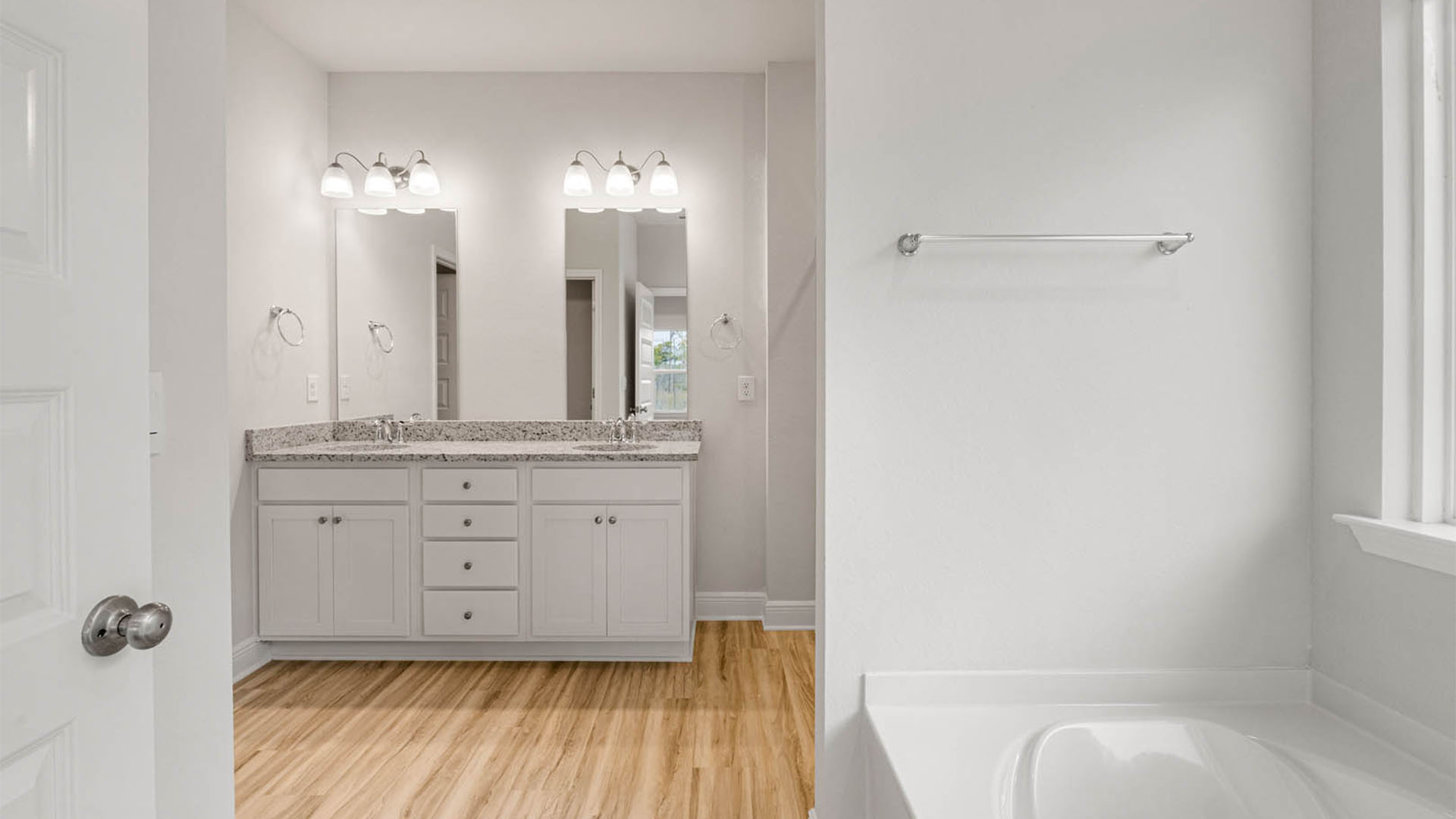 Primary bathroom with double vanity granite countertops and tub and EVP flooring.