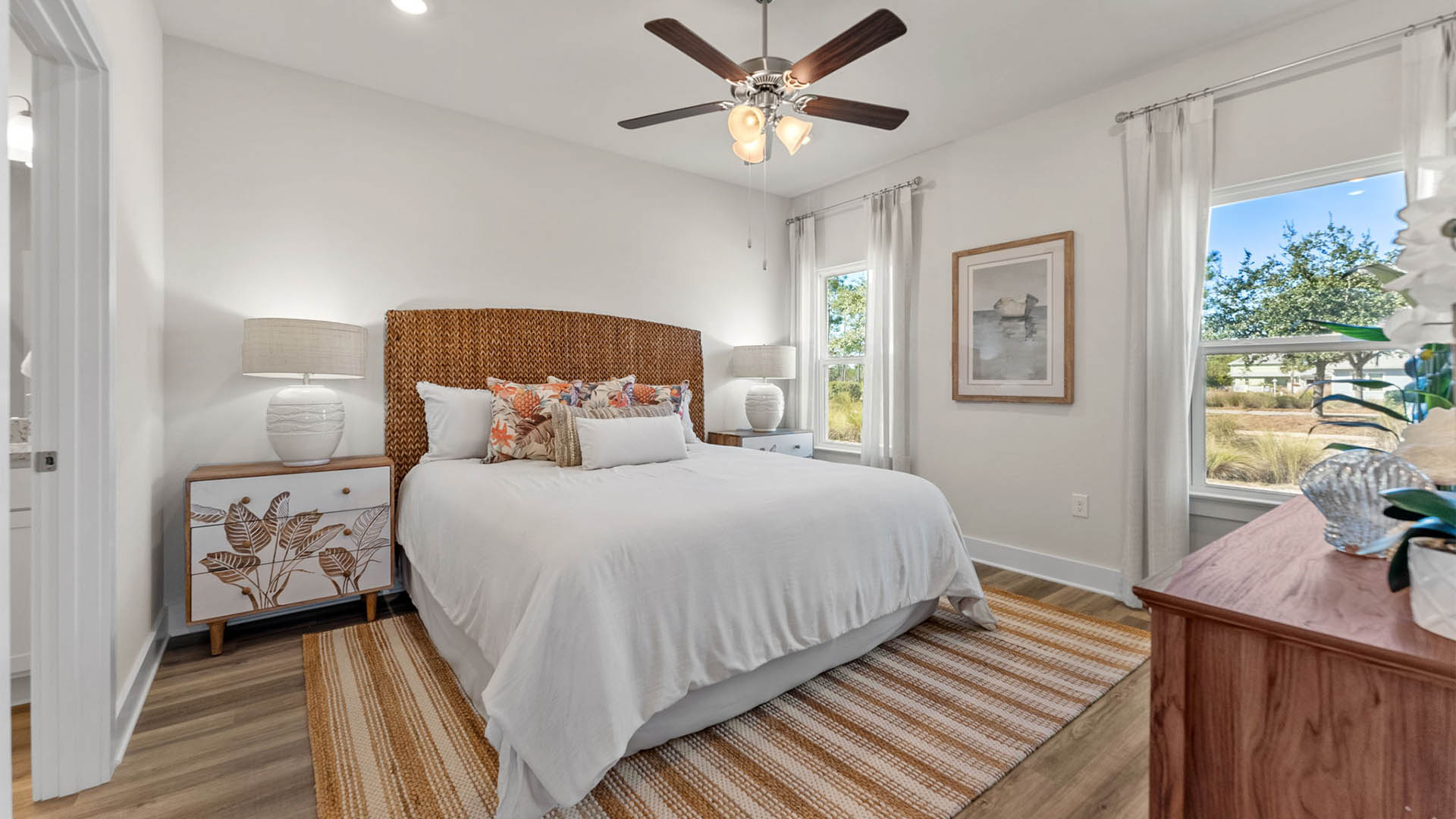 Primary bedroom with EVP flooring with ceiling fan and window and bathroom entrance.
