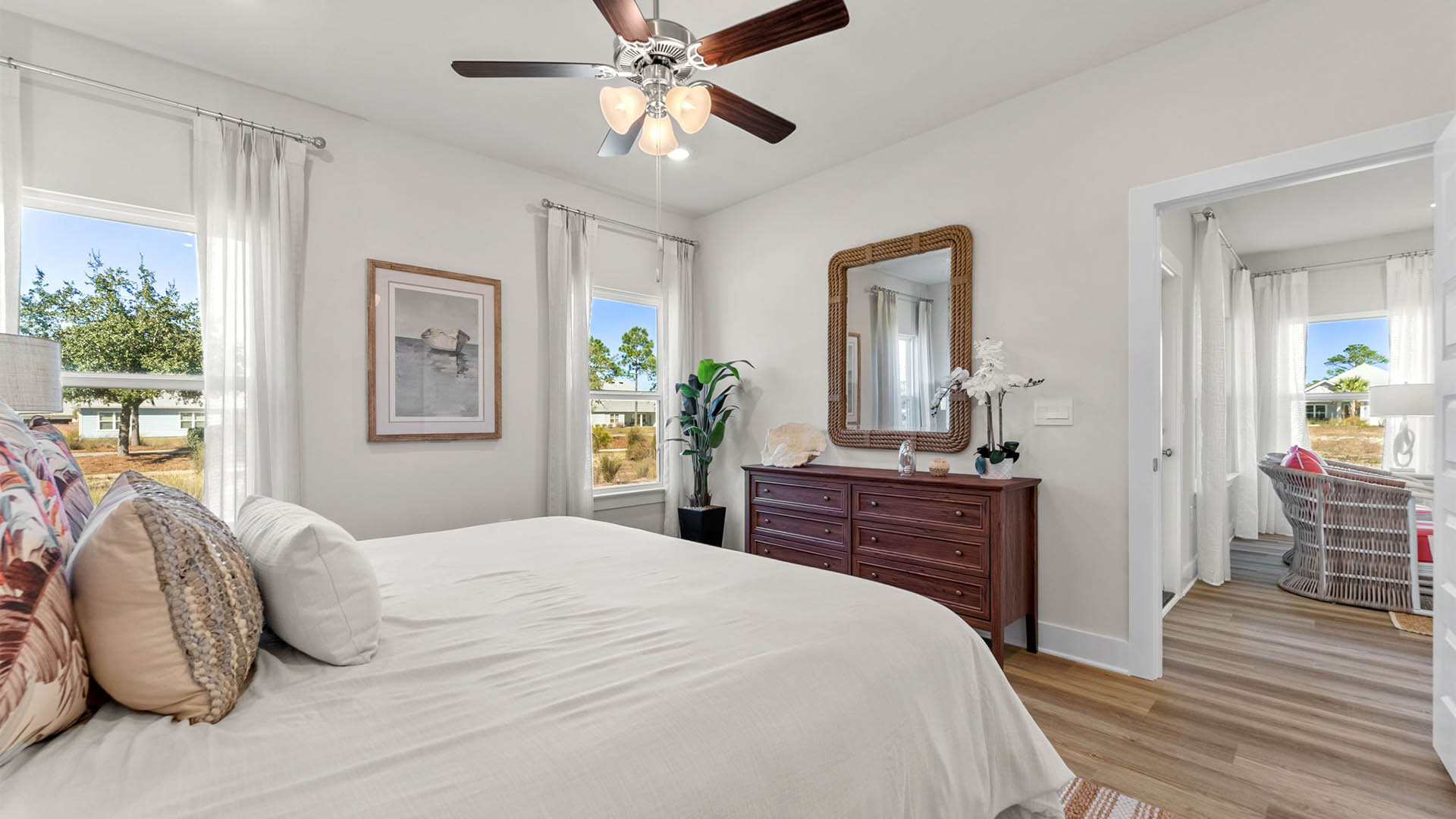 Primary bedroom with EVP flooring with ceiling fan and window and bathroom entrance.