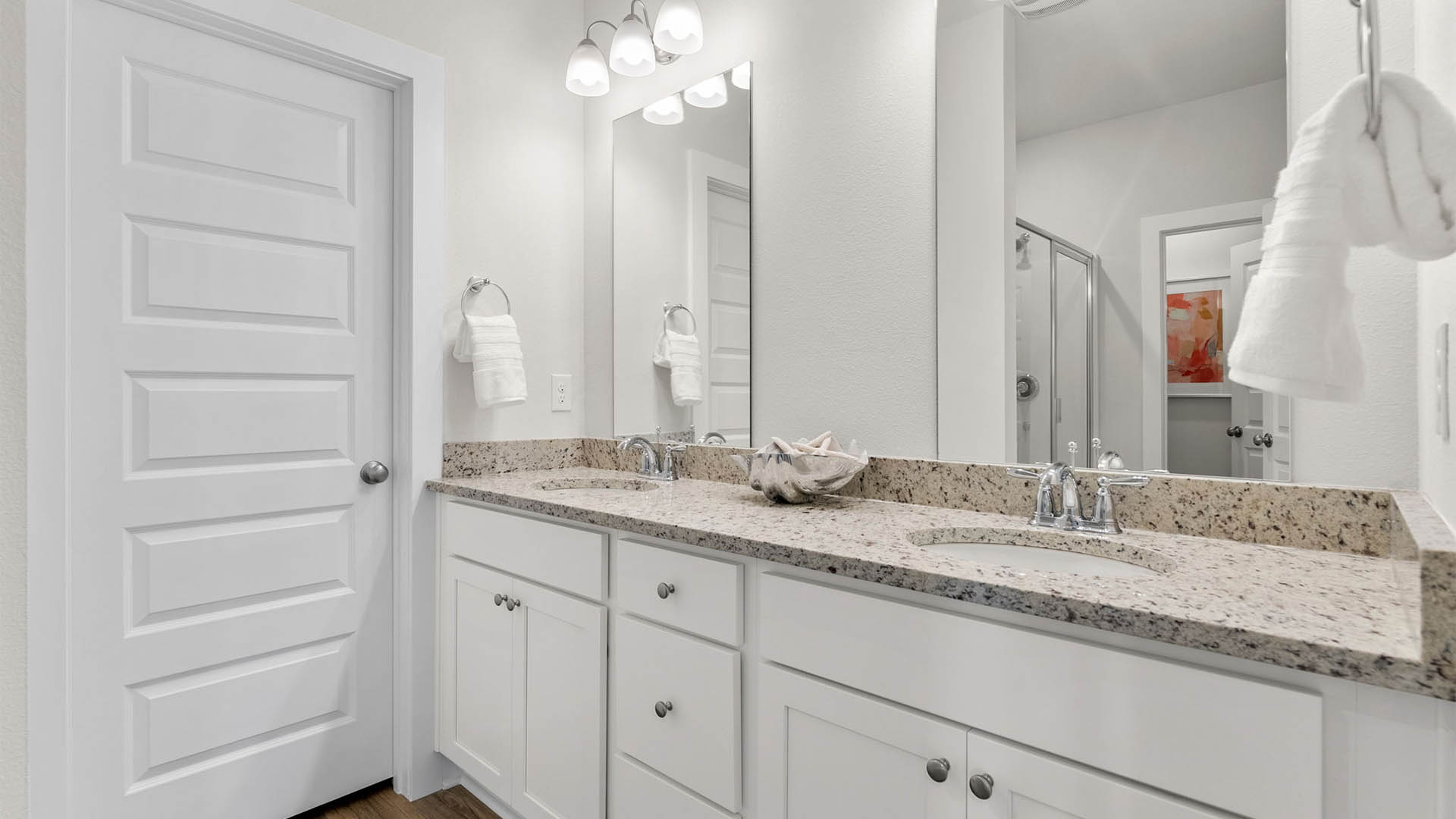 Primary bathroom with double vanity granite countertops and white cabinets and shower and closet with EVP flooring.