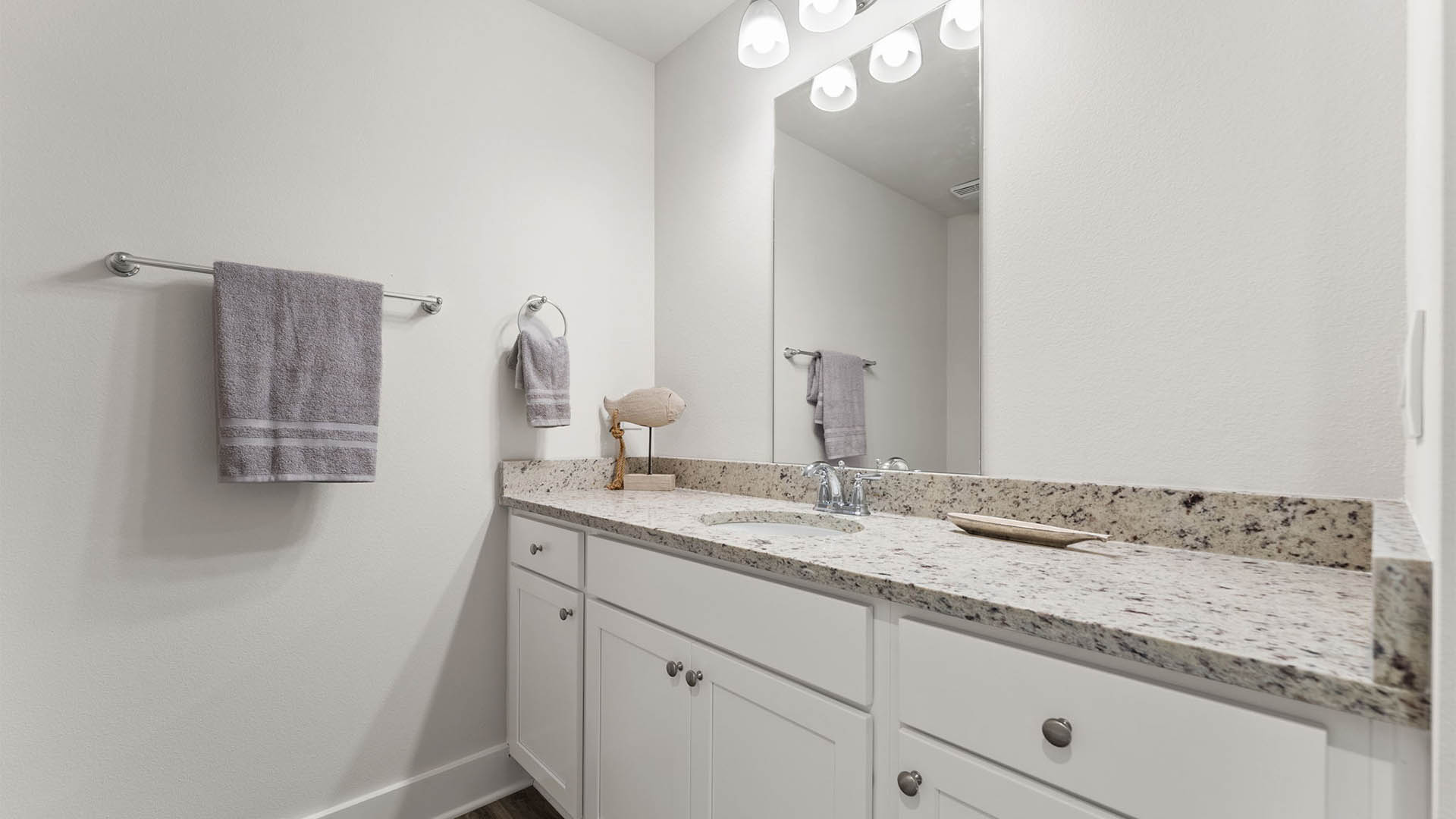 Bathroom with single vanity granite countertops and white cabinets.
