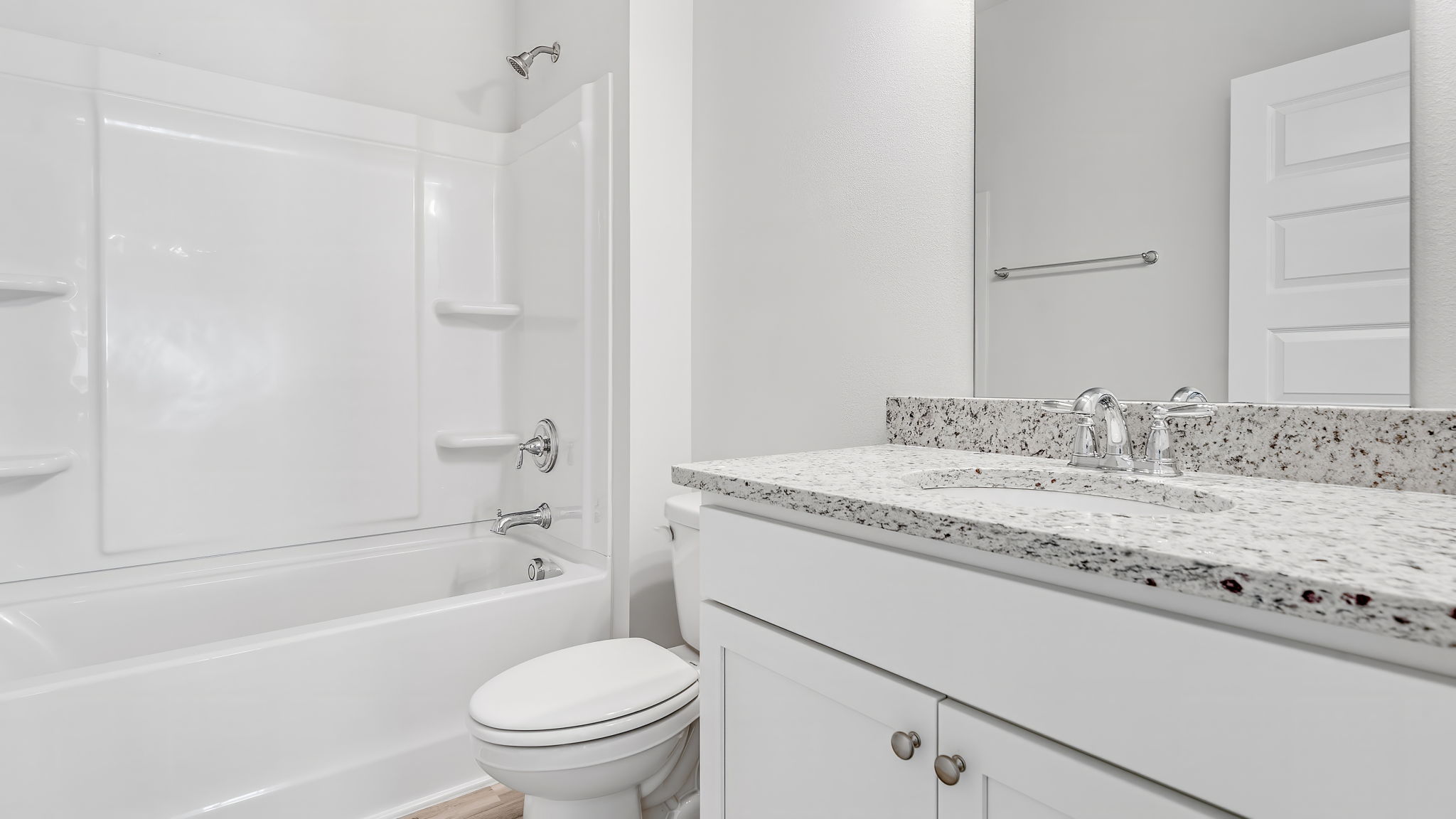 Bathroom with granite countertops and white cabinets and shower.