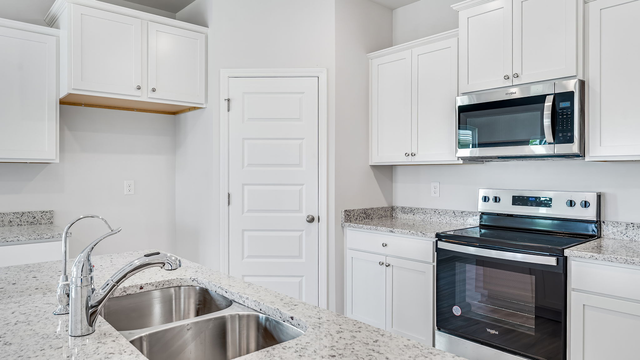 Open kitchen with EVP flooring and granite countertops and stainless-steel appliances and pantry.