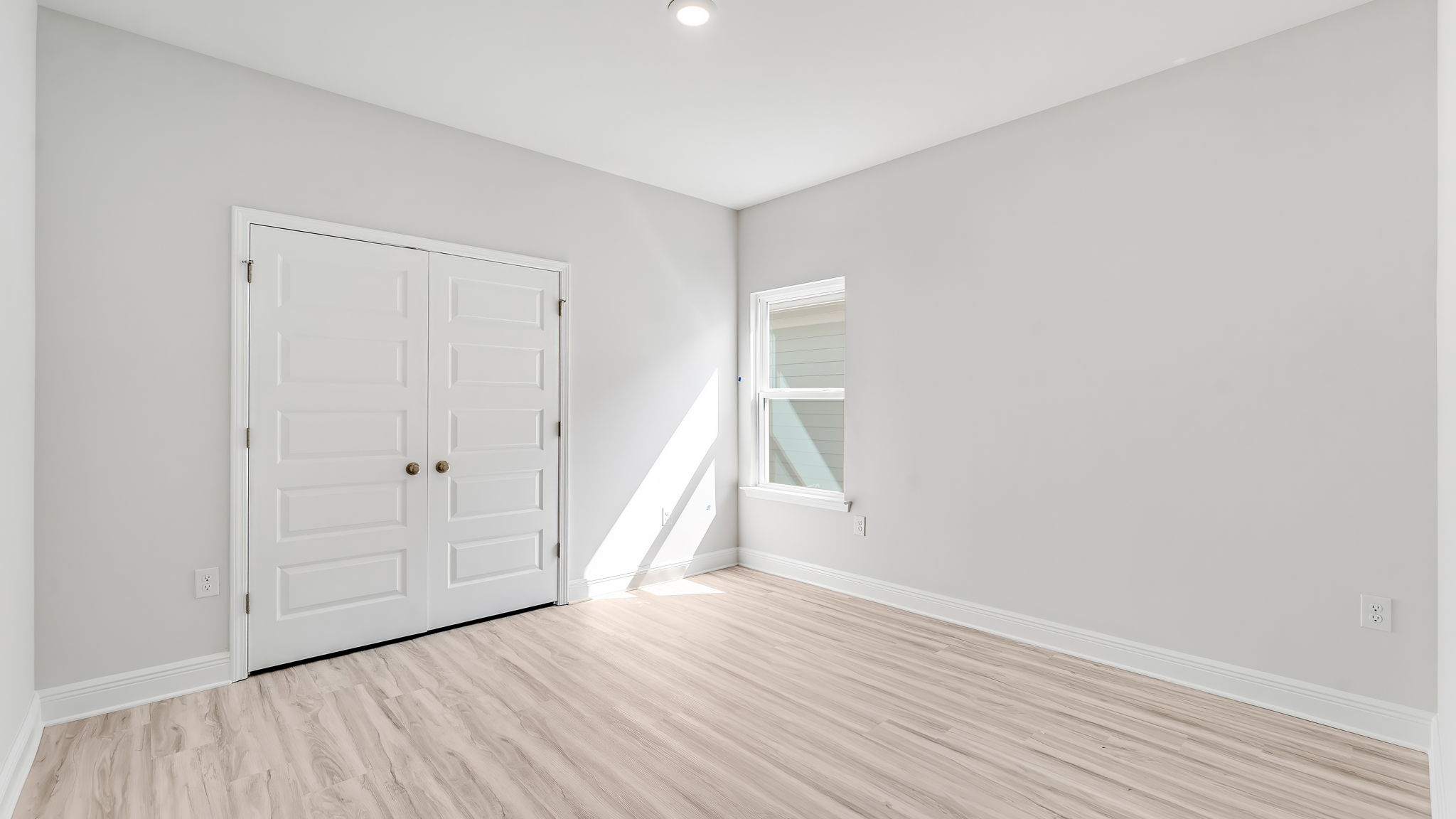 Bedroom with EVP flooring and window and closet.
