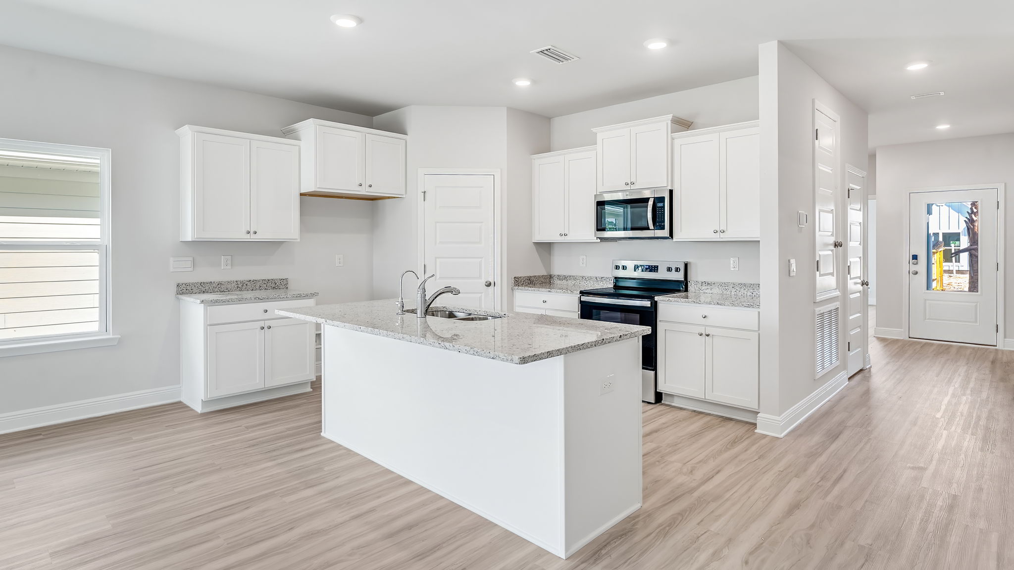 Open kitchen with EVP flooring and granite countertops and stainless-steel appliances and pantry.
