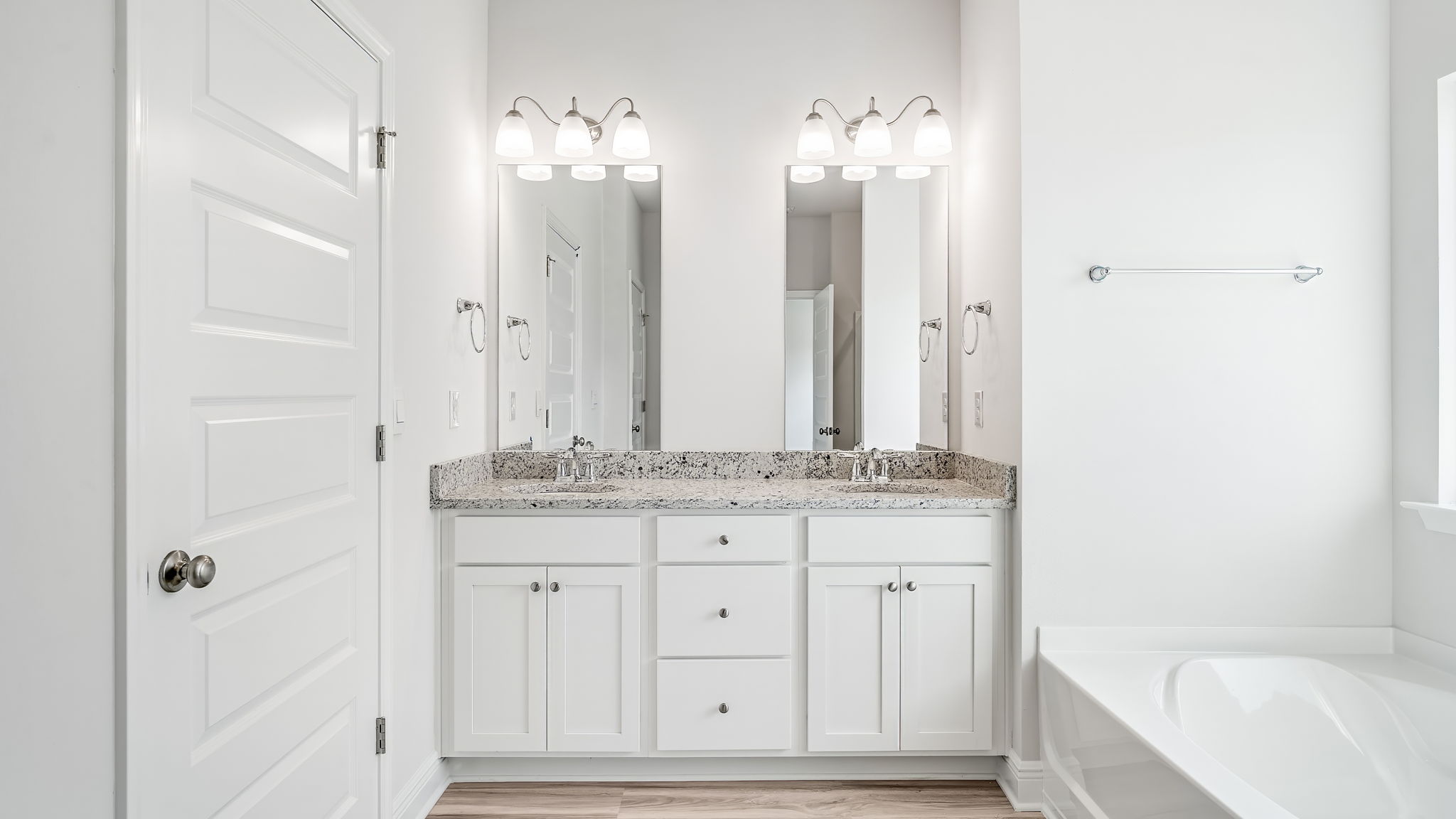 Primary bathroom with double vanity and granite countertops.