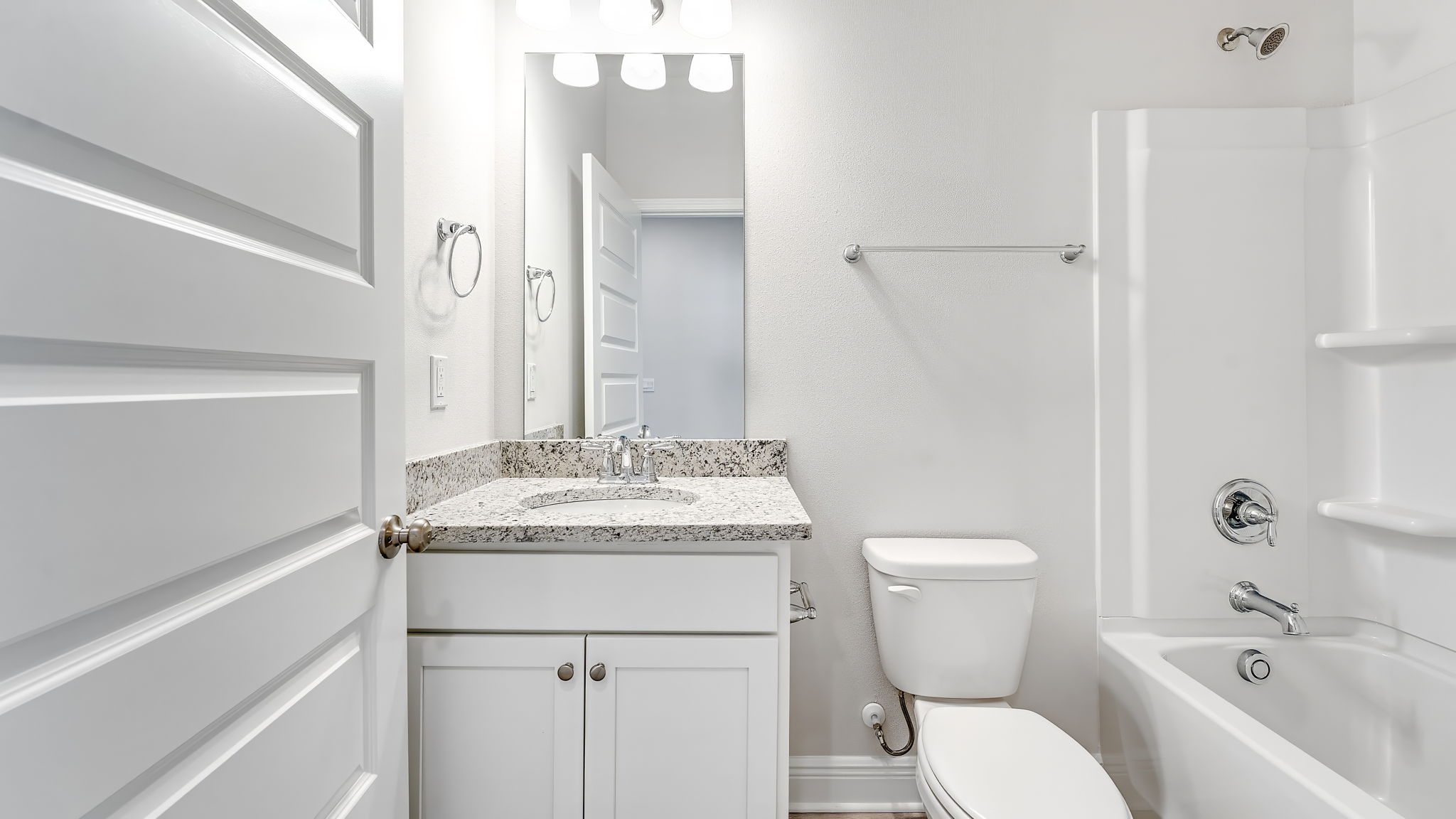 Bathroom with granite countertops and white cabinets and shower.