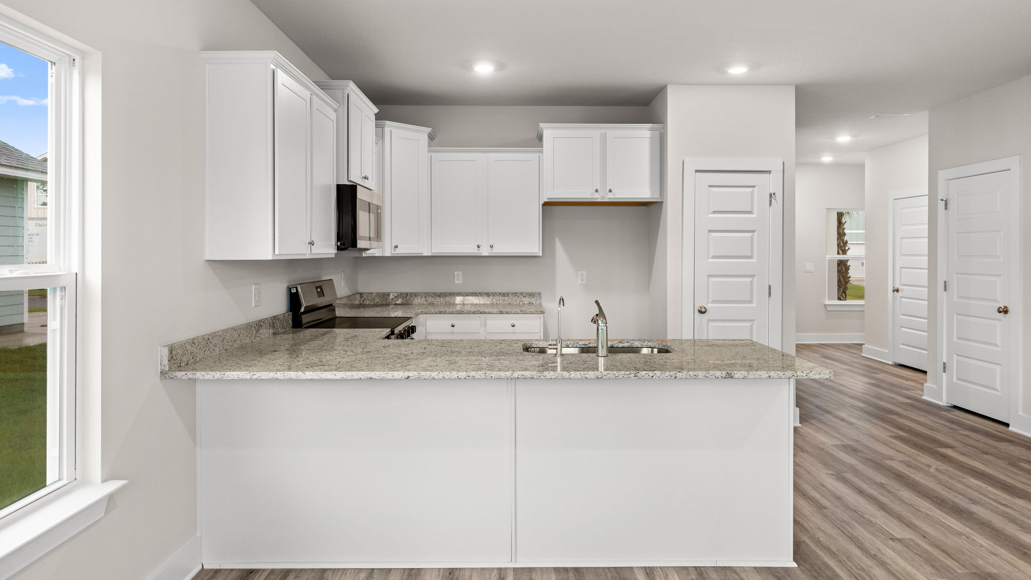 Kitchen with granite countertops and white cabinets and stainless-steel appliances.