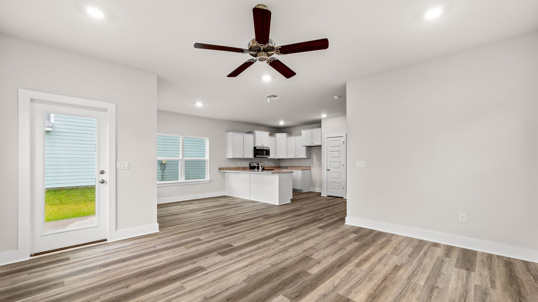 Living room with EVP flooring and ceiling fan and windows and back door.