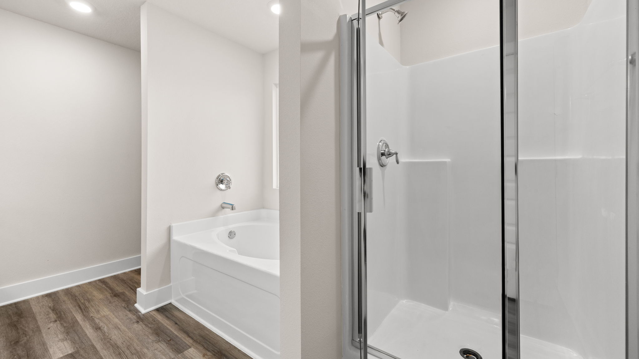 Primary bathroom tub and shower with glass doors.