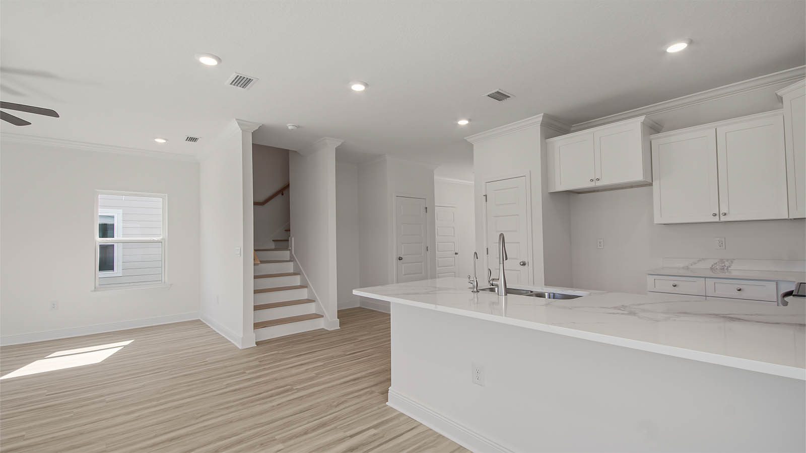 Kitchen and hallway with stairs and foyer.