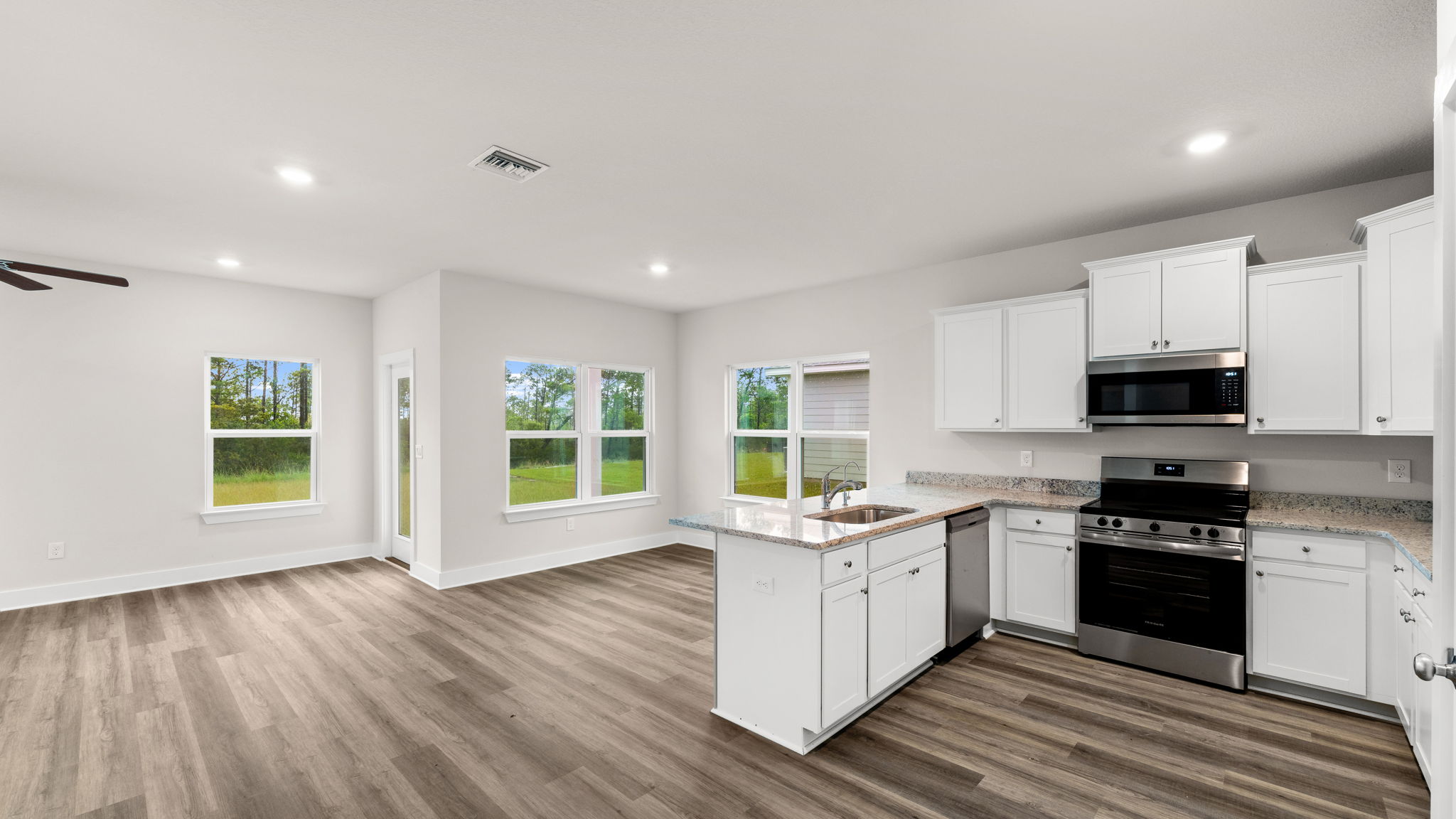 Kitchen with granite countertops and white cabinets and stainless-steel appliances.