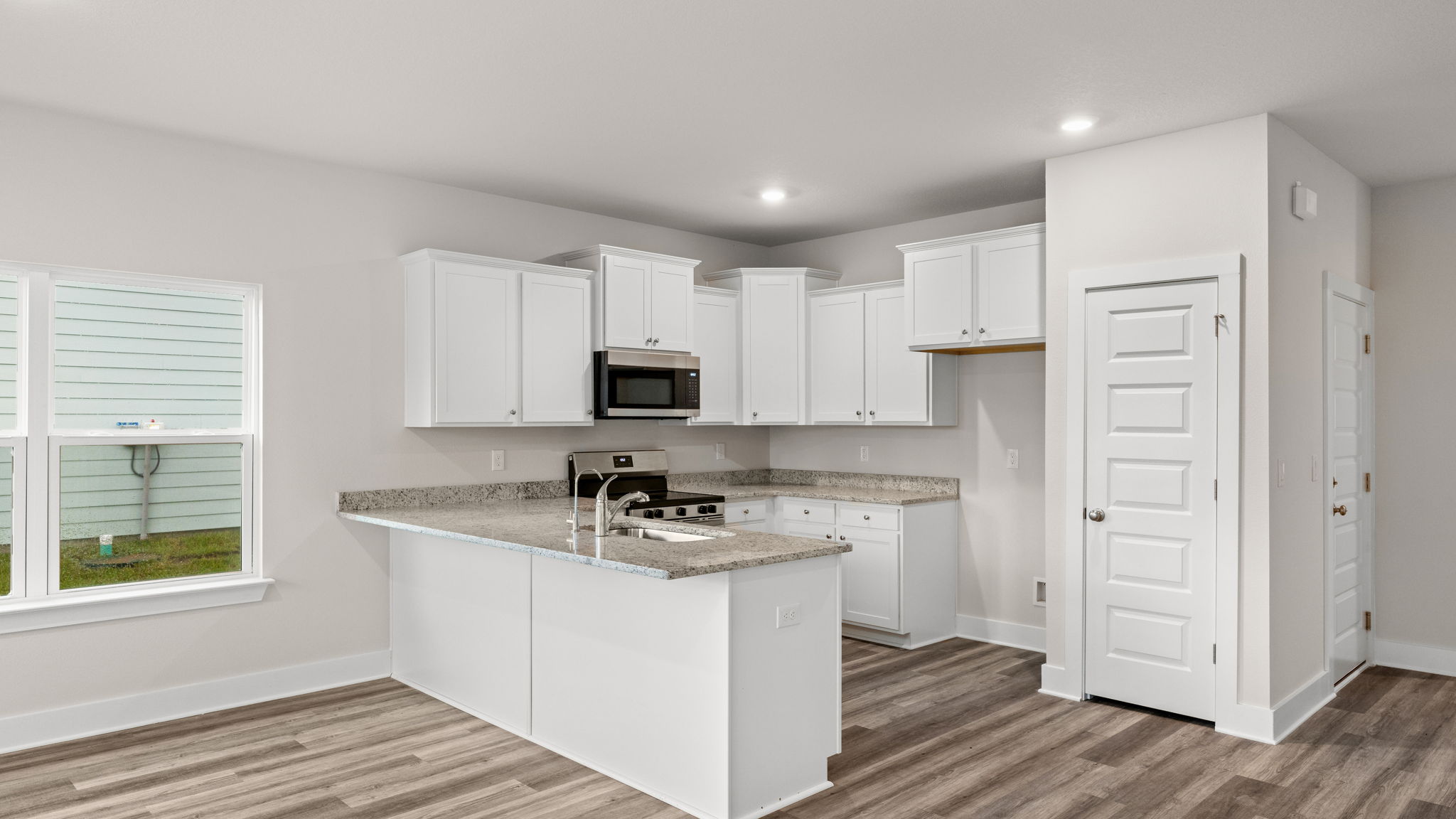 Kitchen with granite countertops and white cabinets and stainless-steel appliances.