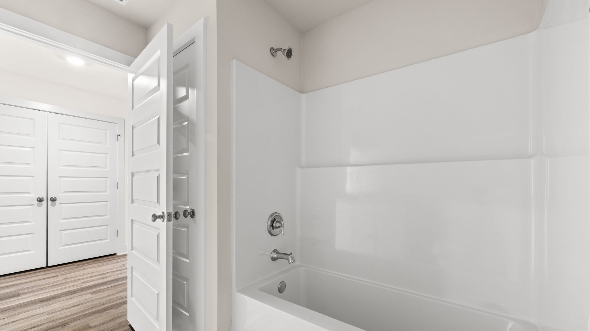 Bathroom with shower and hallway entrance.