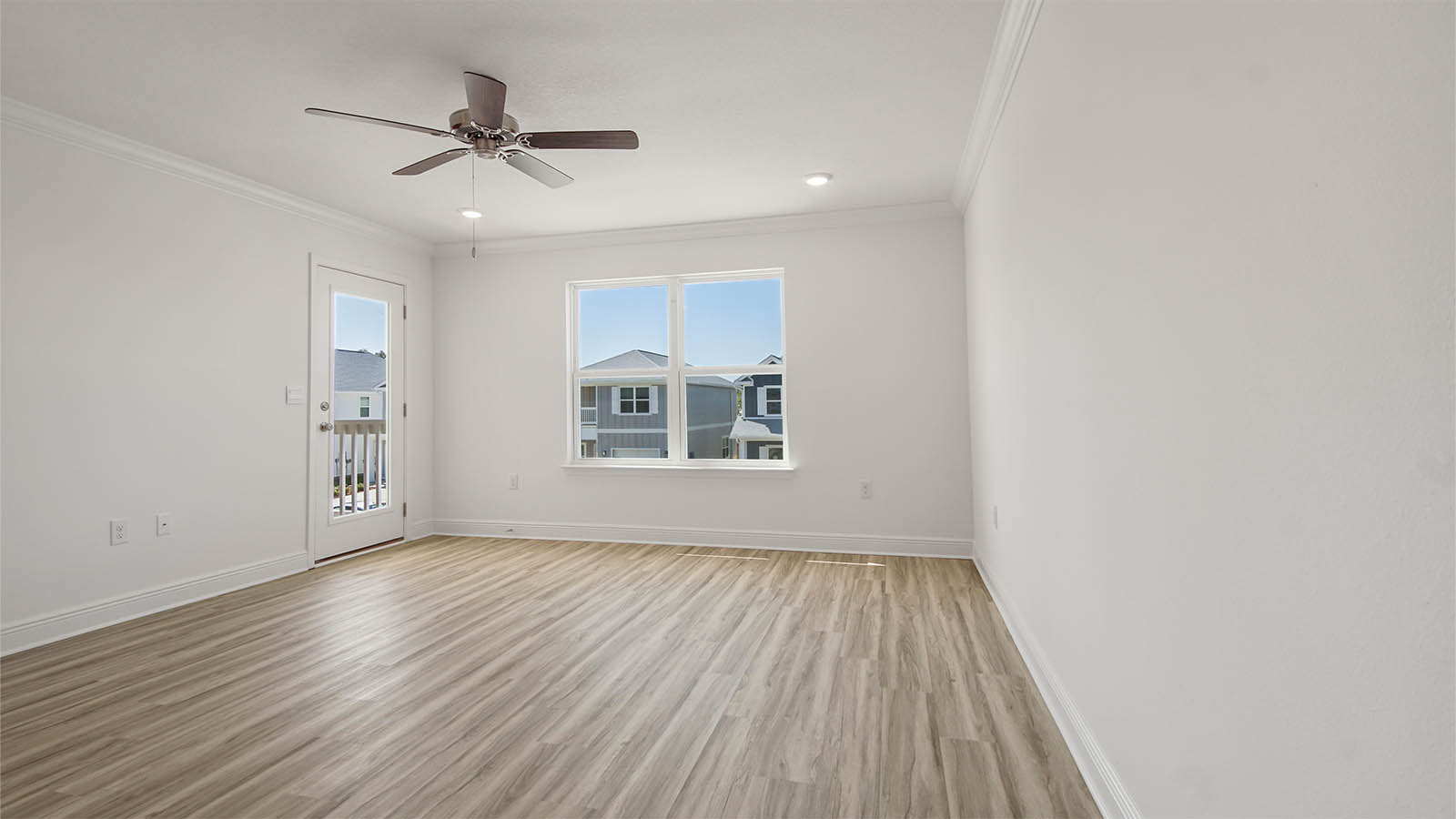 Primary bedroom with EVP flooring and balcony door and ceiling fan.