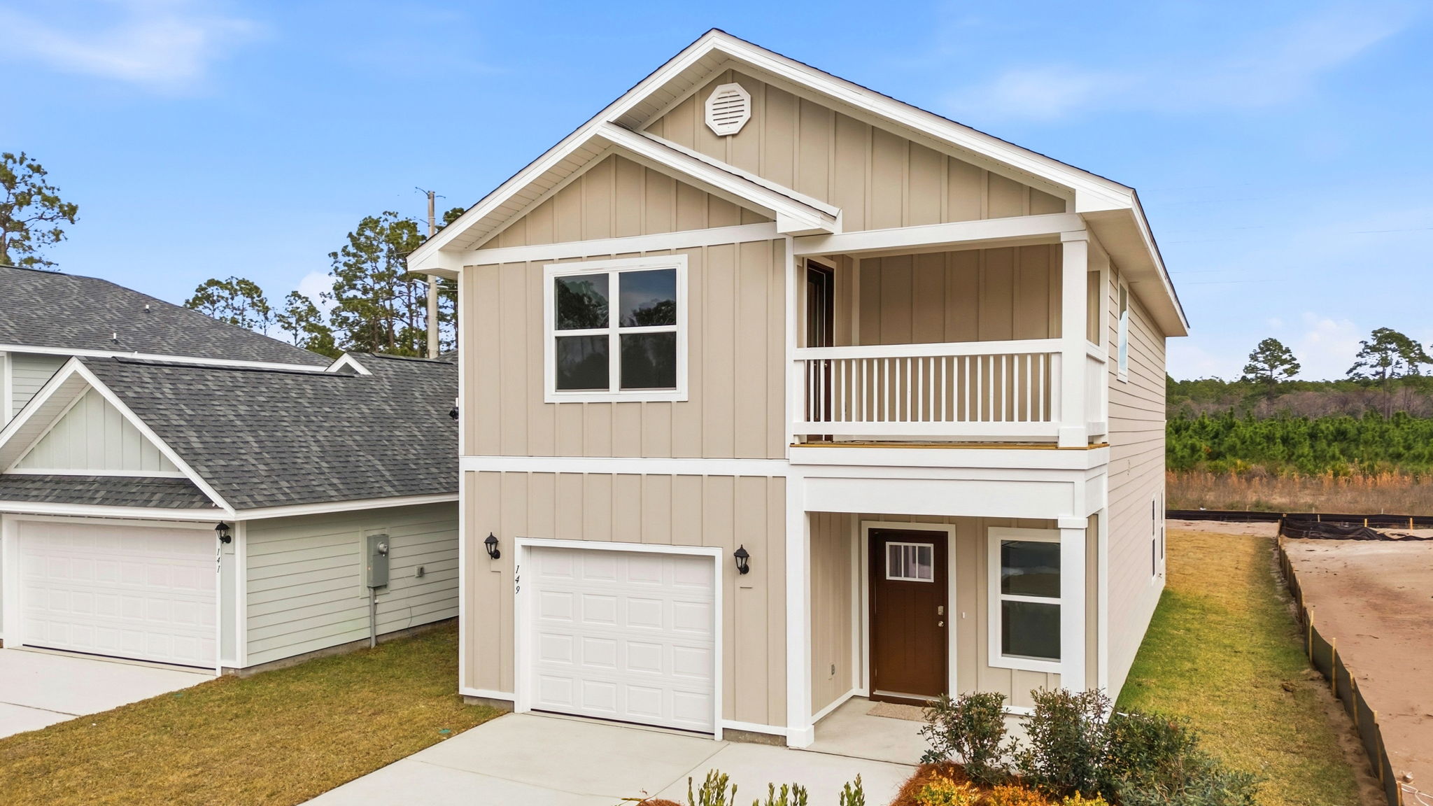 Monroe floor plan at WindMark Beach with Hardie siding and covered front porch and balcony and 1 car garage.
