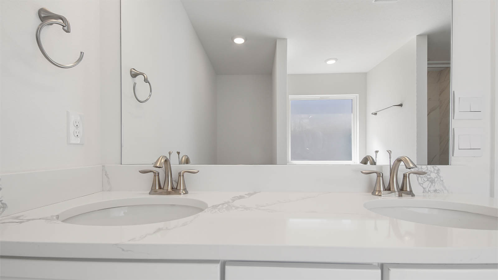 Primary bathroom with EVP flooring and double vanity quartz countertops and white cabinets.