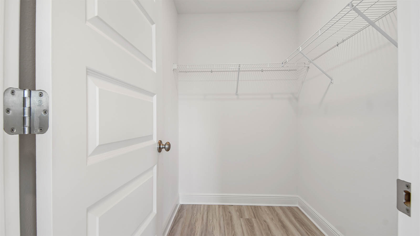 Primary bathroom walk-in closet with EVP flooring and ventilated shelving.