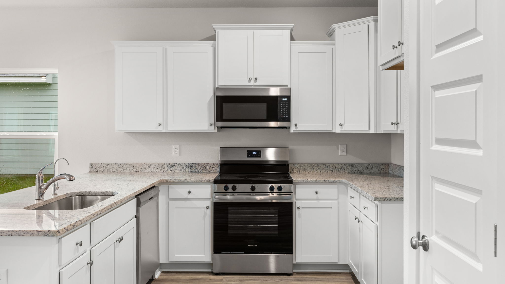 Kitchen with granite countertops and white cabinets and stainless-steel appliances.