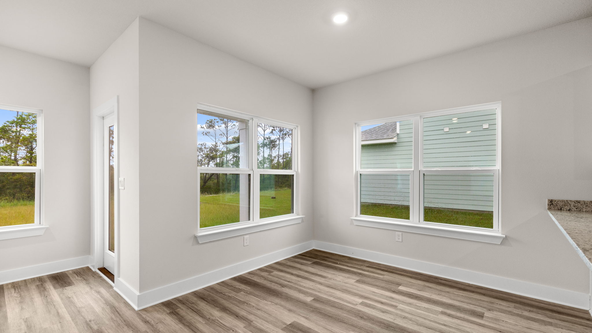 Dining area next to kitchen with windows.