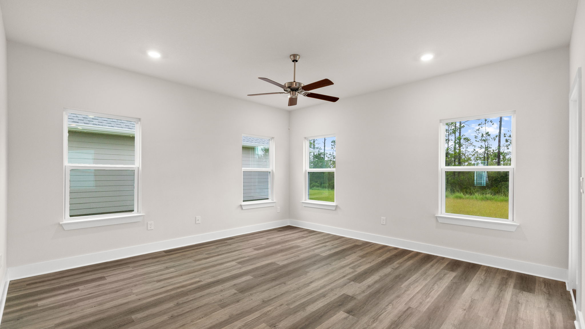 Living room with EVP flooring and ceiling fan and windows.
