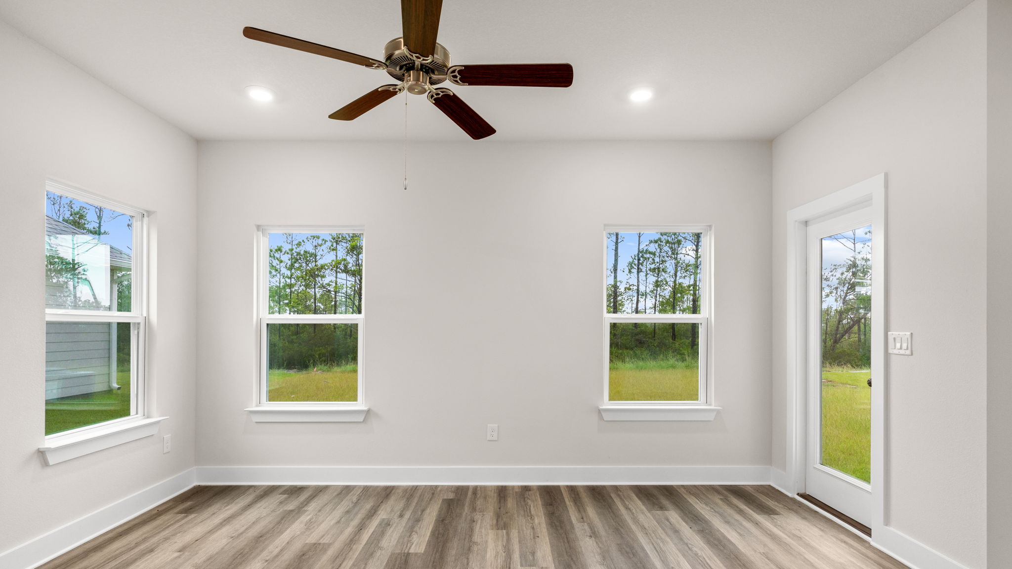 Living room with EVP flooring and ceiling fan and windows and back door.