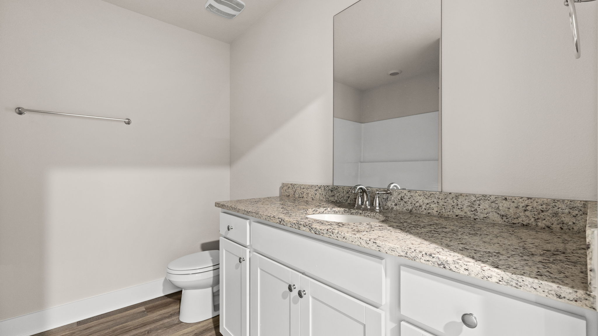 Bathroom with EVP flooring and single vanity granite countertops and white cabinets.
