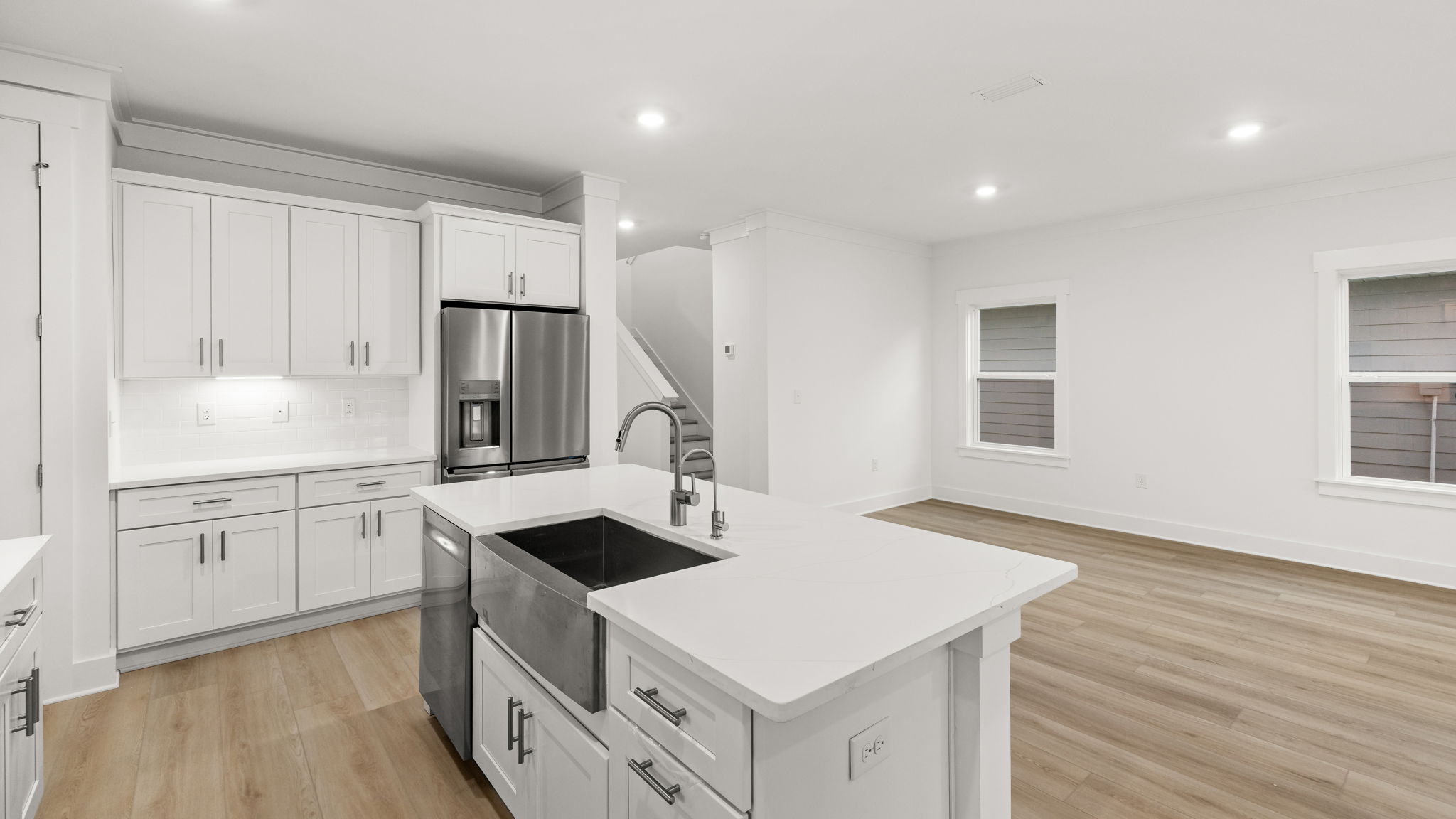 Open kitchen with island and quartz countertops and white cabinets and stainless-steel appliances.