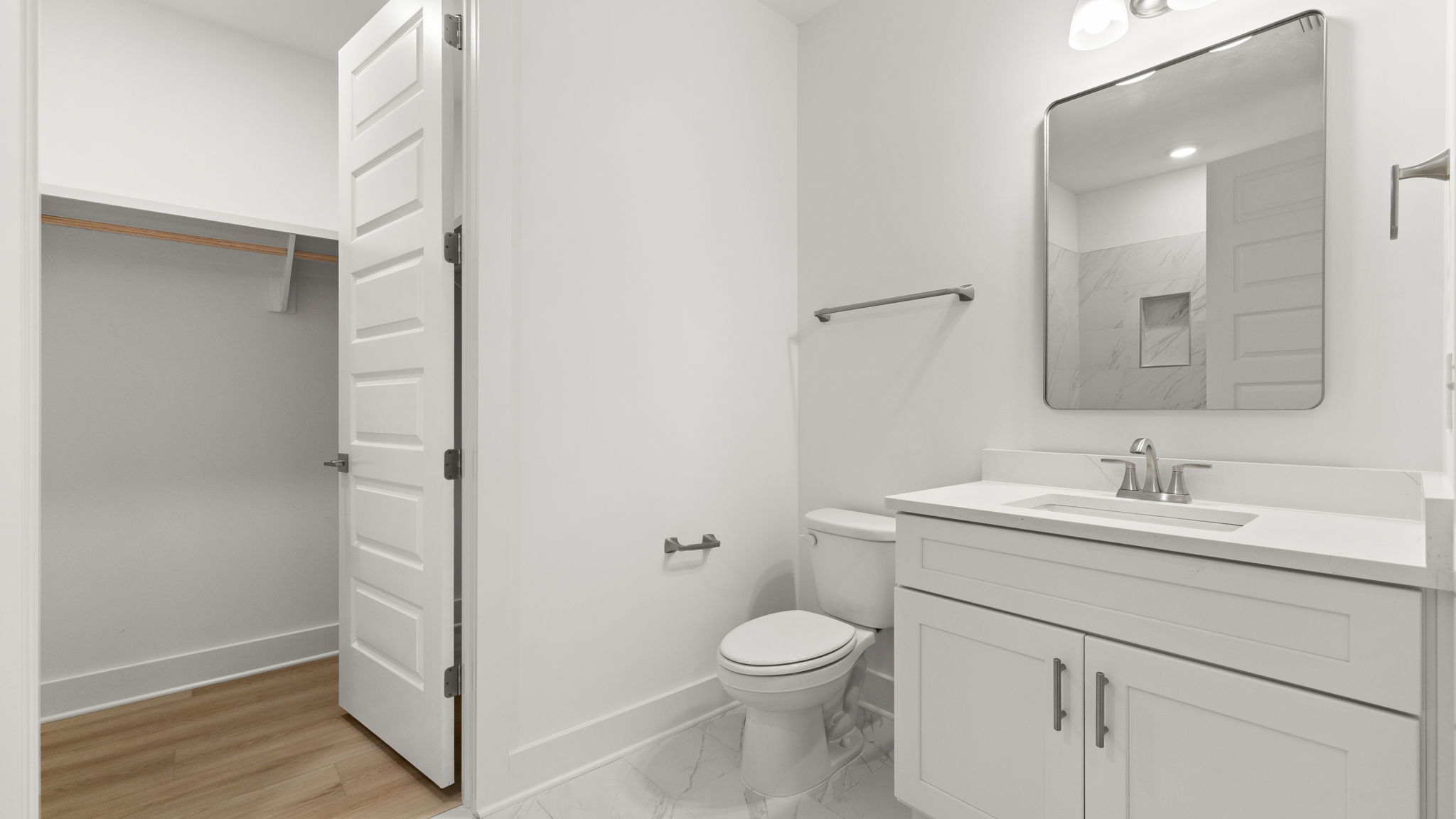 Bathroom with single vanity quartz countertops and toilet and closet.