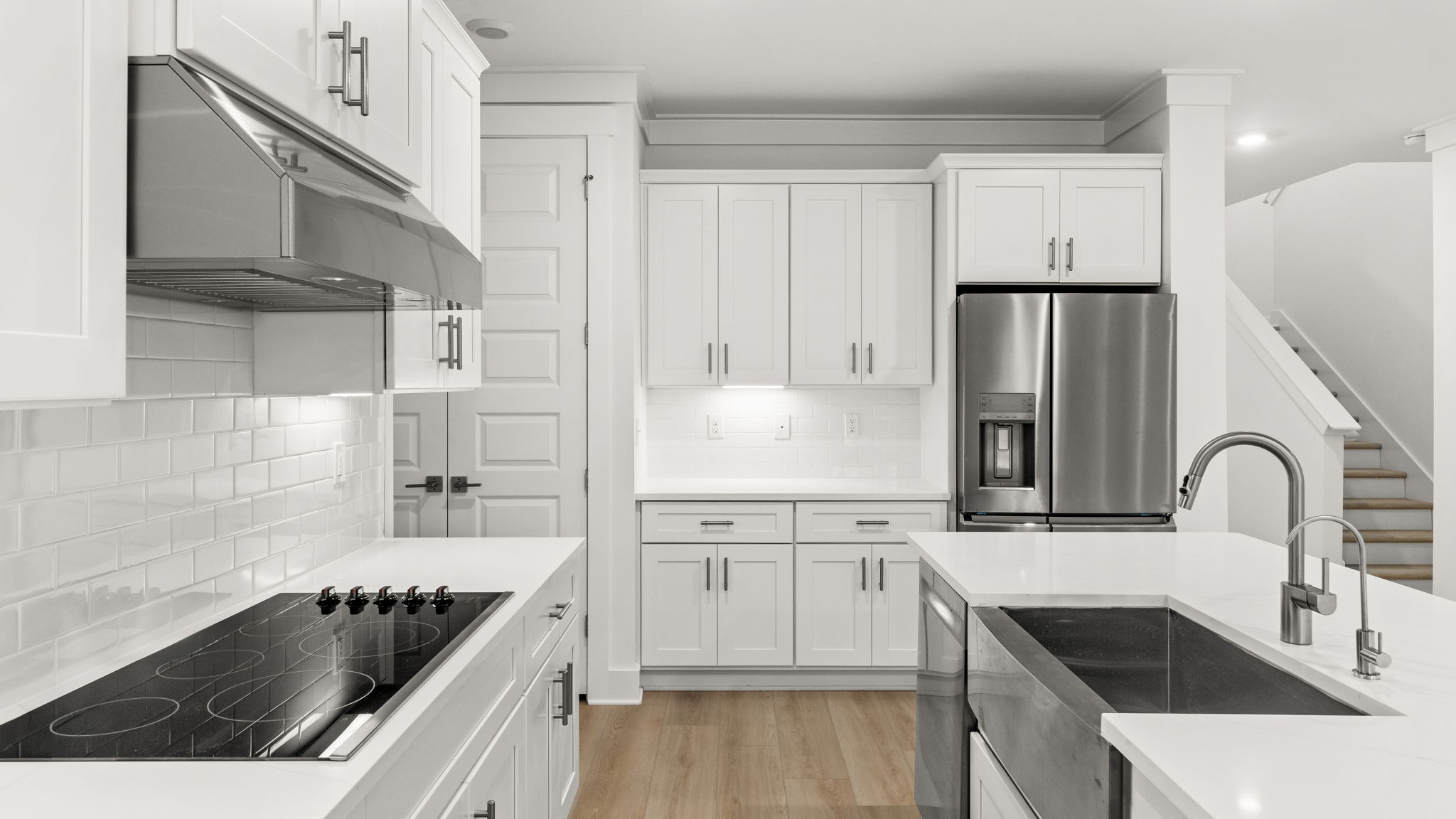 Open kitchen with island and quartz countertops and white cabinets and stainless-steel appliances.
