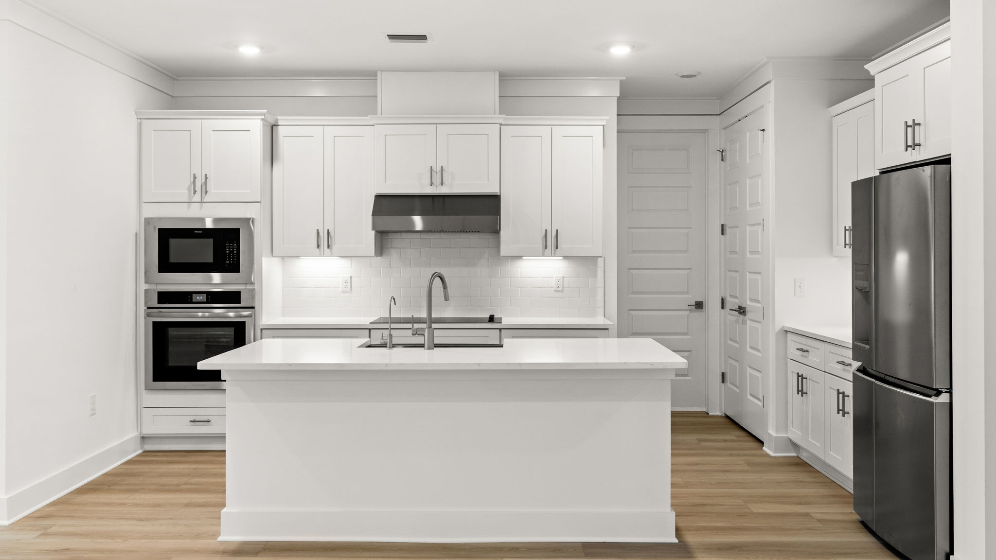 Open kitchen with island and quartz countertops and white cabinets and stainless-steel appliances.