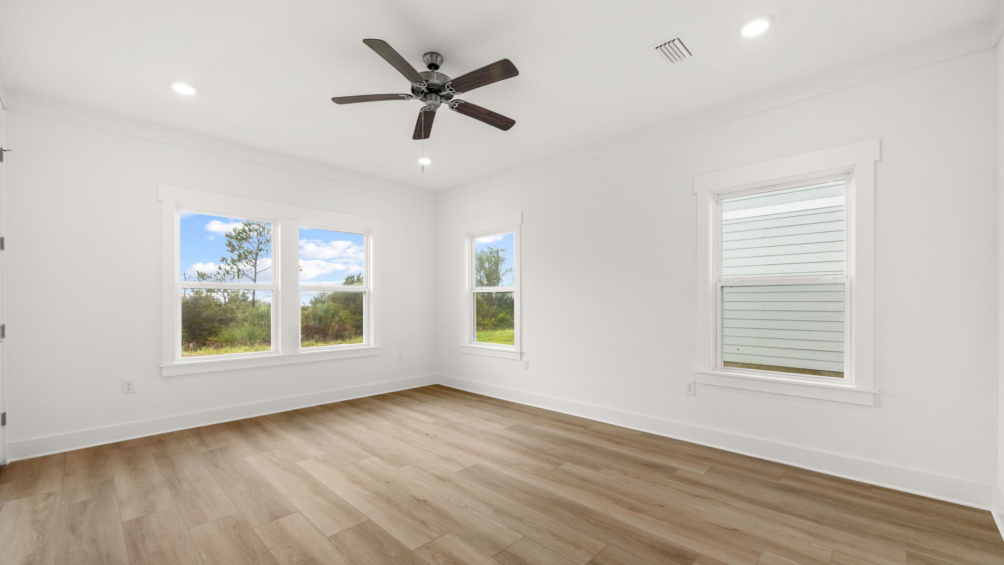 Primary bedroom with ceiling fan and windows and EVP flooring.