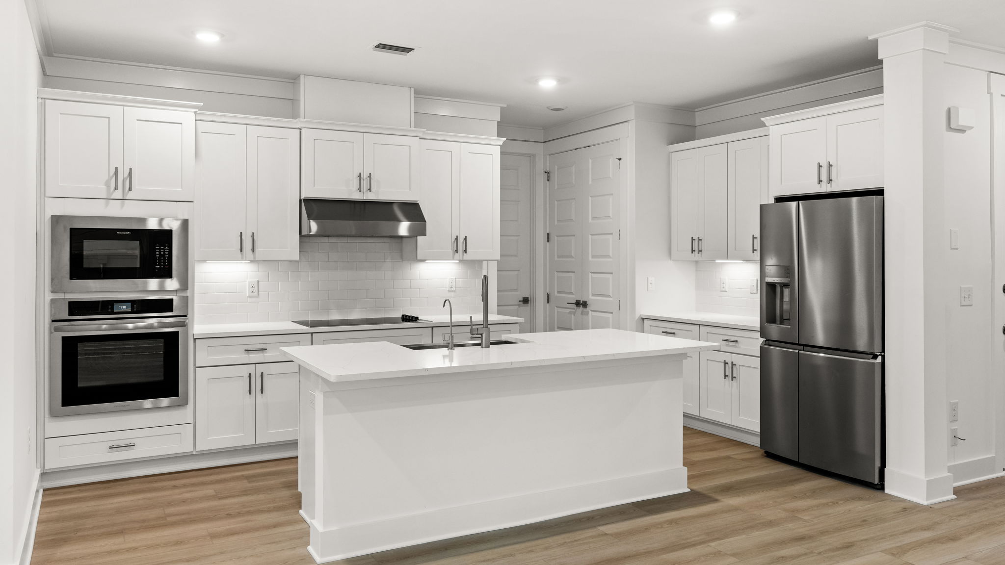 Open kitchen with island and quartz countertops and white cabinets and stainless-steel appliances.