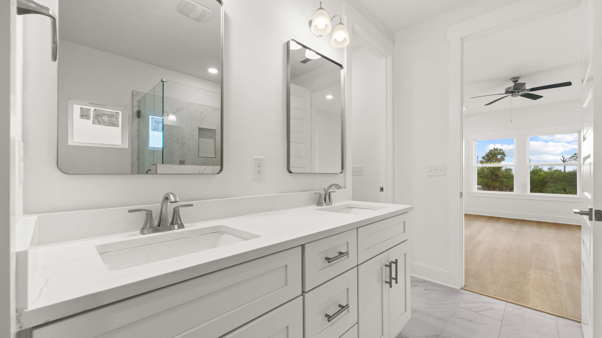 Primary bathroom with double vanity quartz countertops and tile floor and white cabinets.