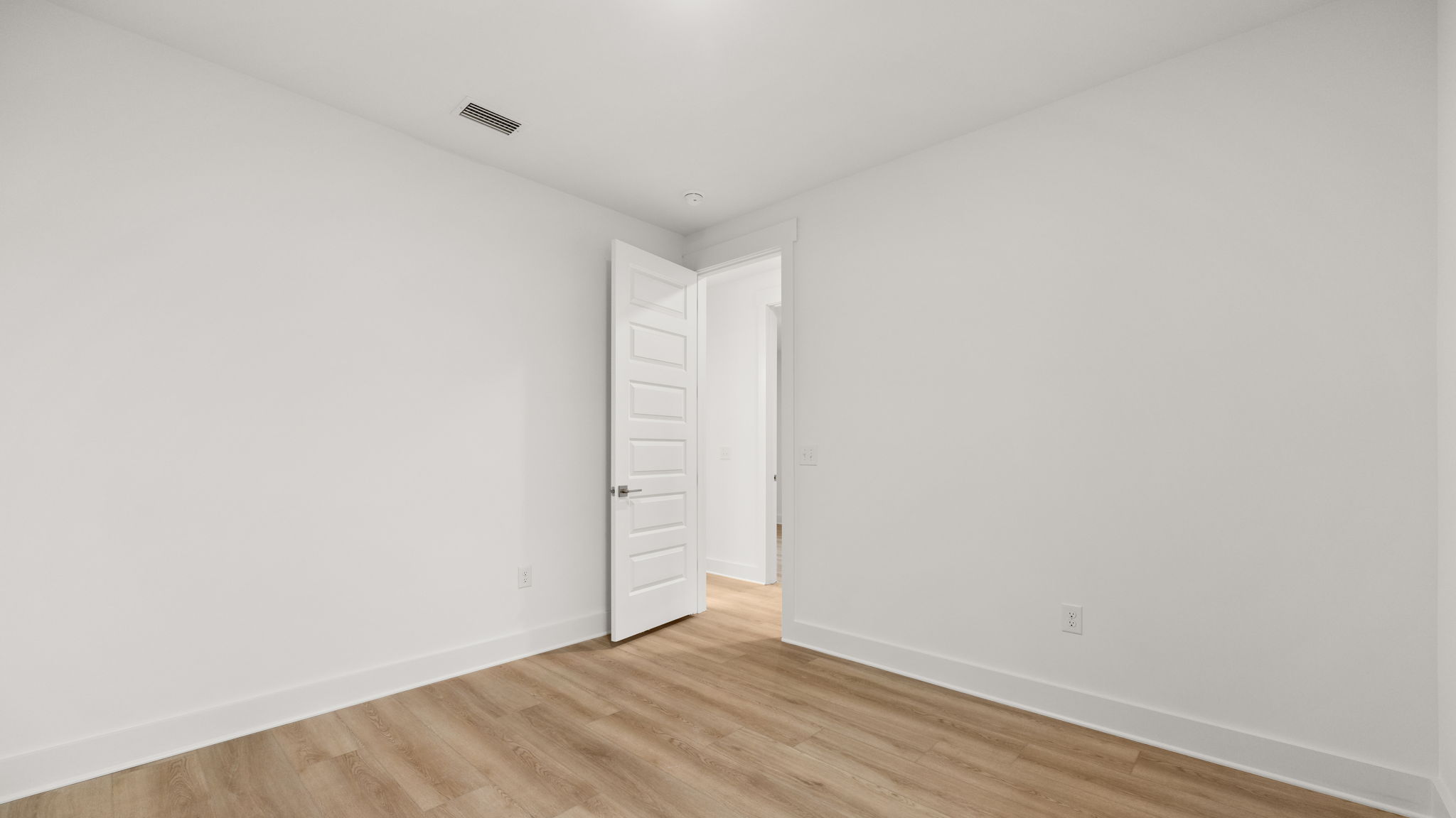 Bedroom with EVP flooring and hallway entrance.