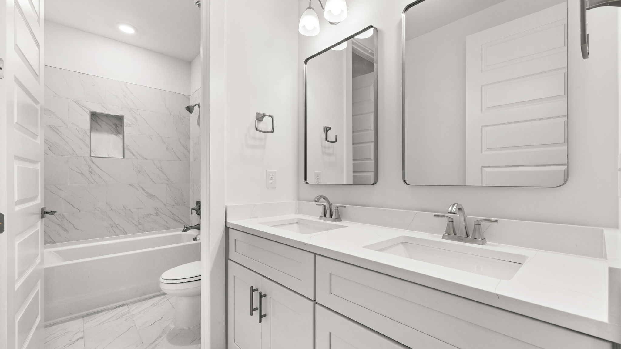 Bathroom with double vanity quartz countertops and toilet and tile tub.