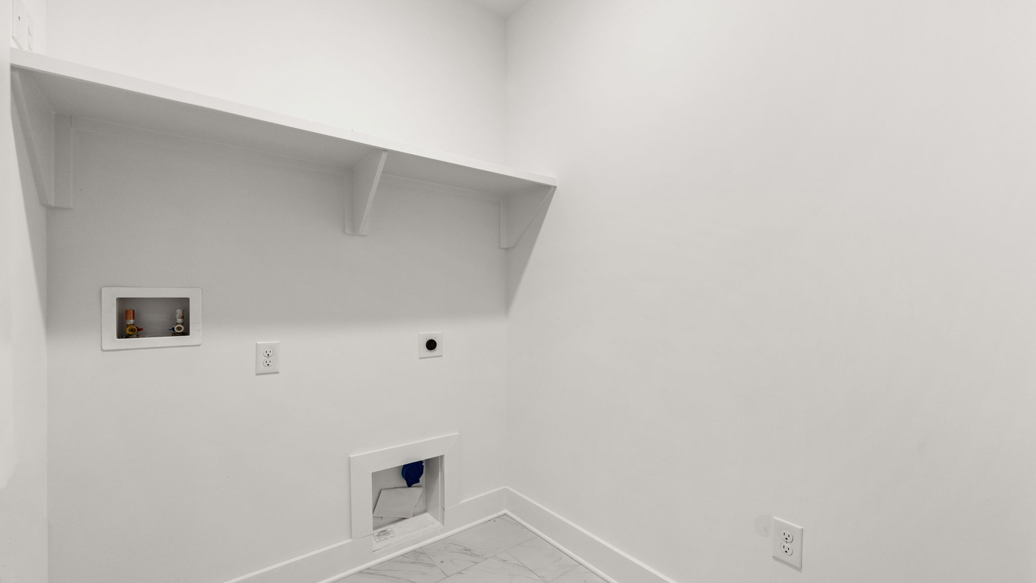 Laundry room with tile flooring and wood shelving.