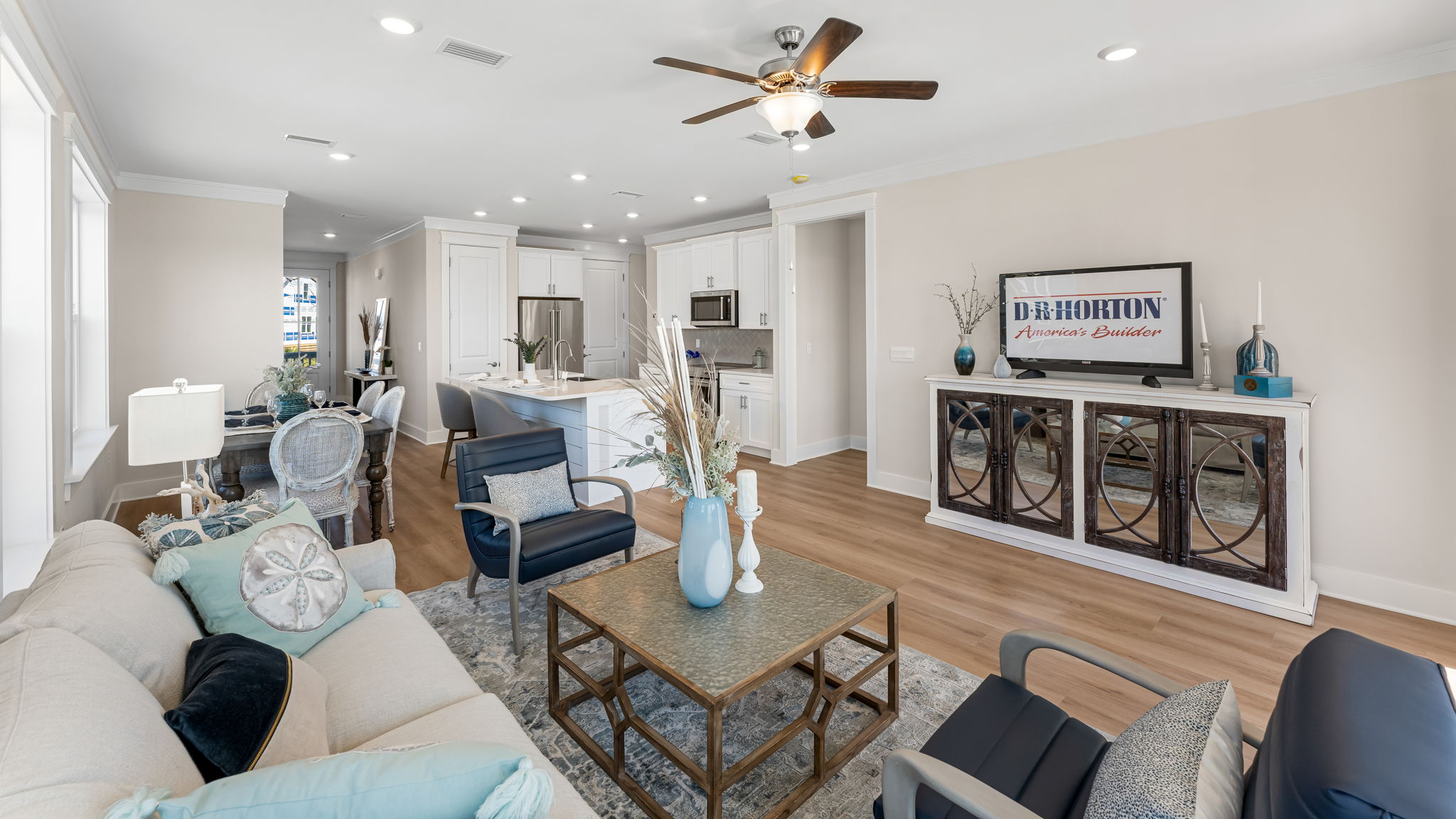 Open furnished living room with EVP flooring and ceiling fan and large windows.